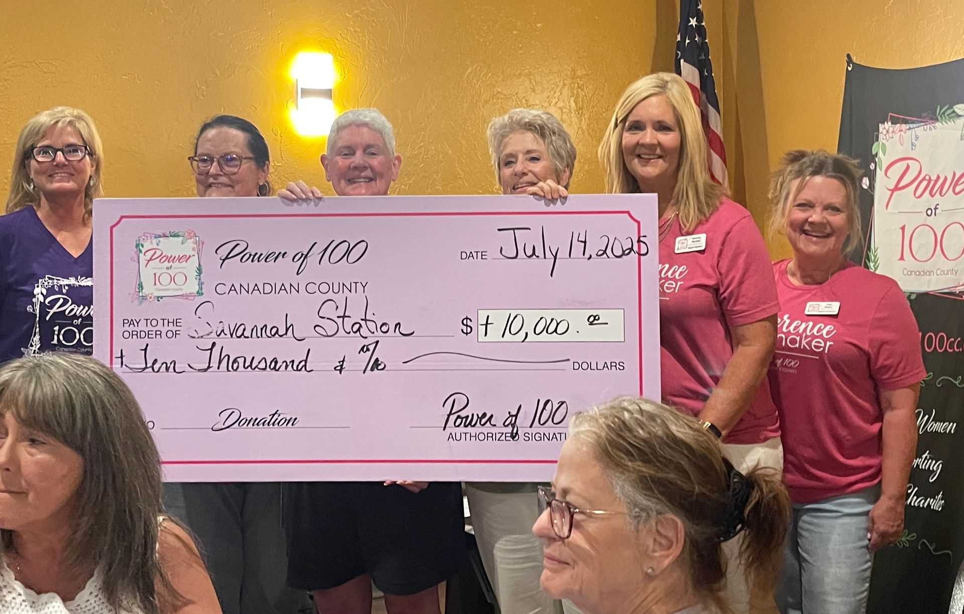 A group of people standing next to each other holding a large pink check.