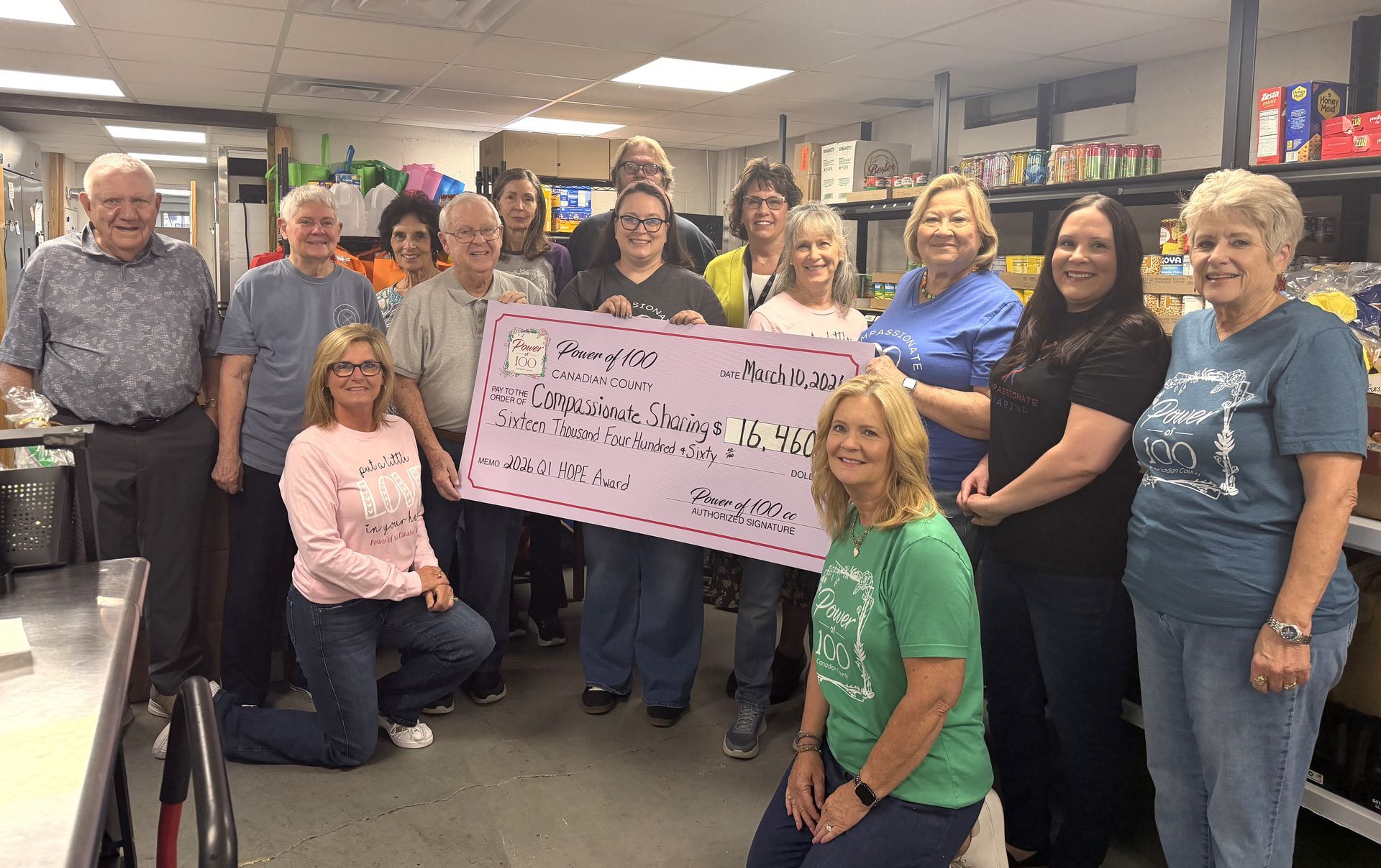 A group of people standing next to each other holding a large pink check.