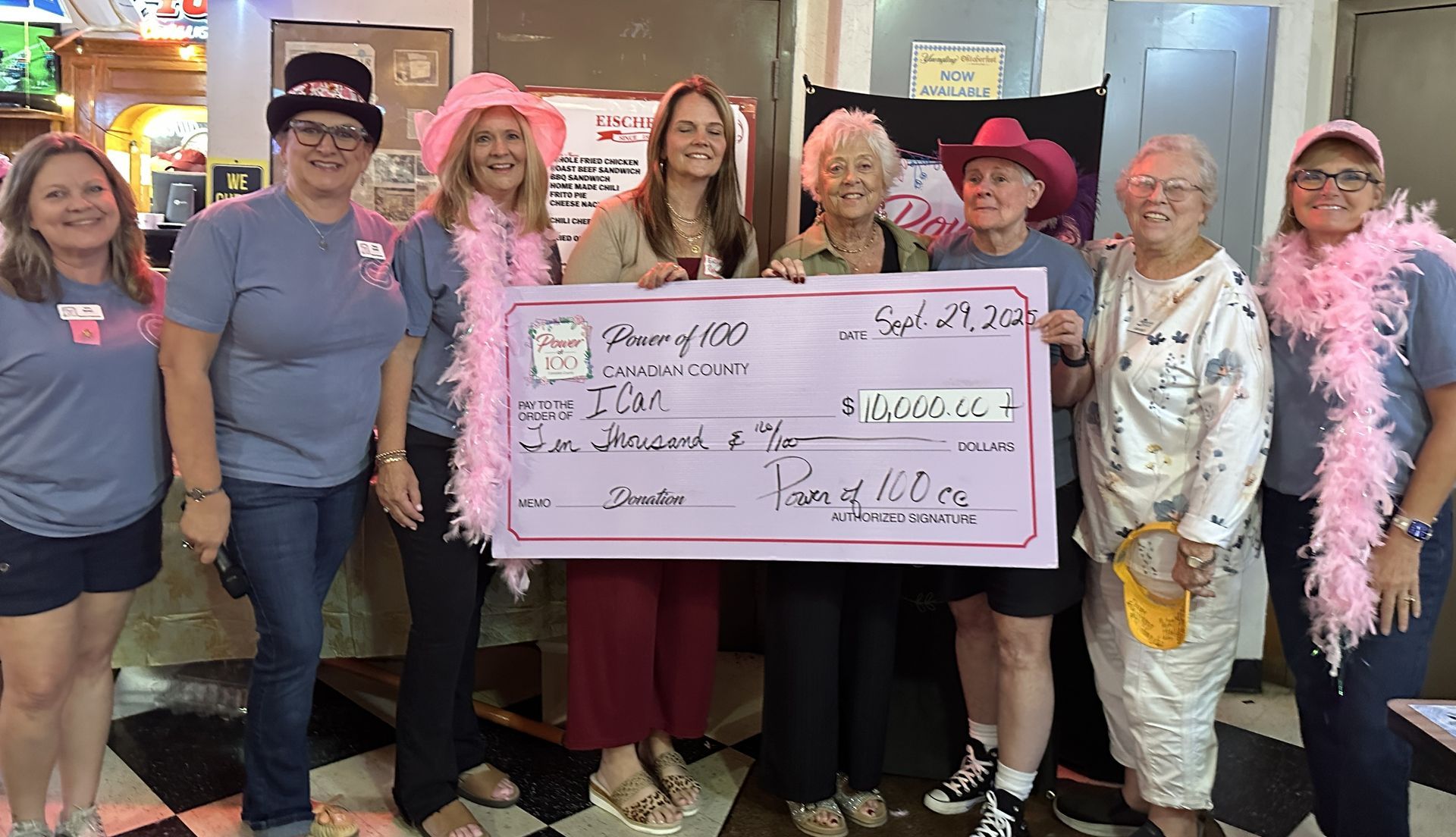A group of people standing next to each other holding a large pink check.
