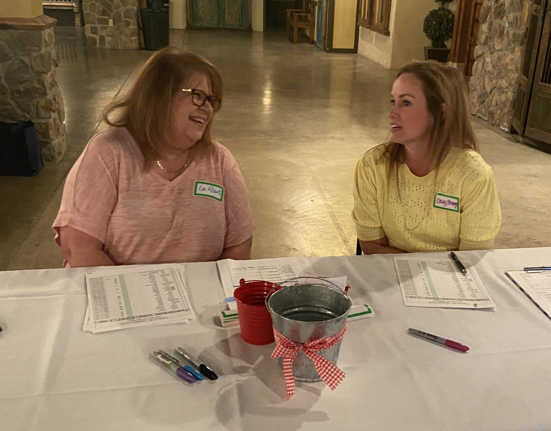 Two women are sitting at a table talking to each other.