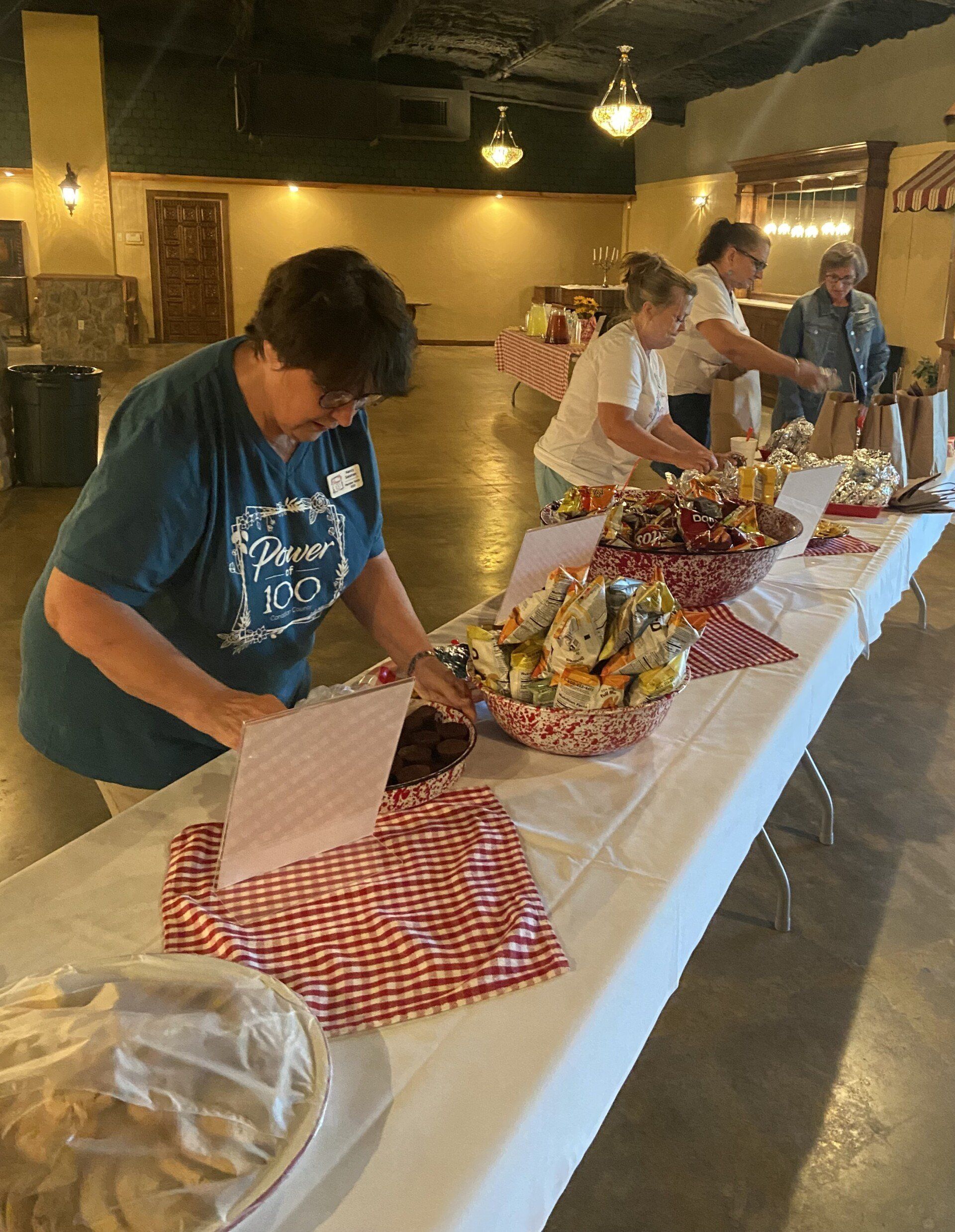 A group of people are standing around a table with food on it.