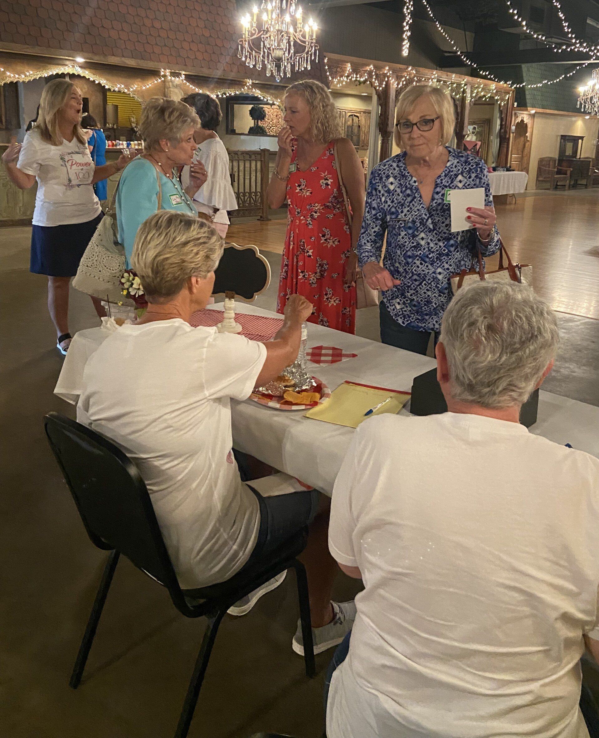 A group of women are sitting at a table talking to each other.