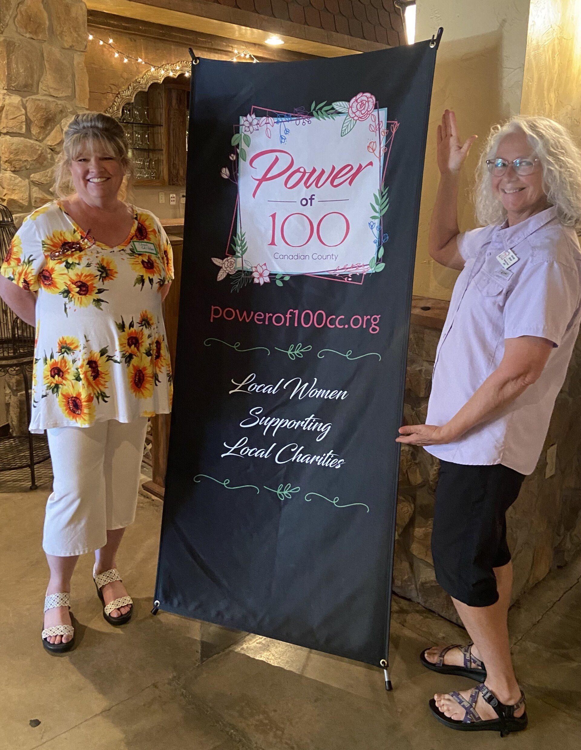 Two women are standing next to a banner that says power at 100