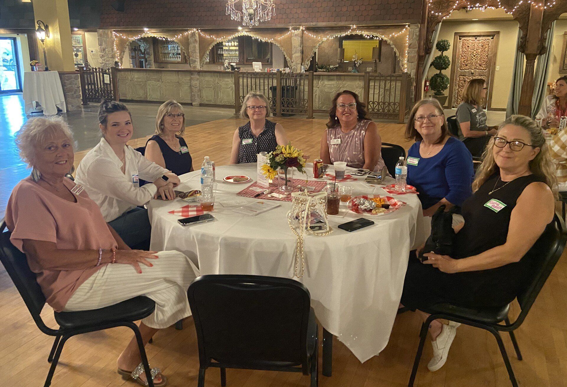 A group of women are sitting around a table in a room.