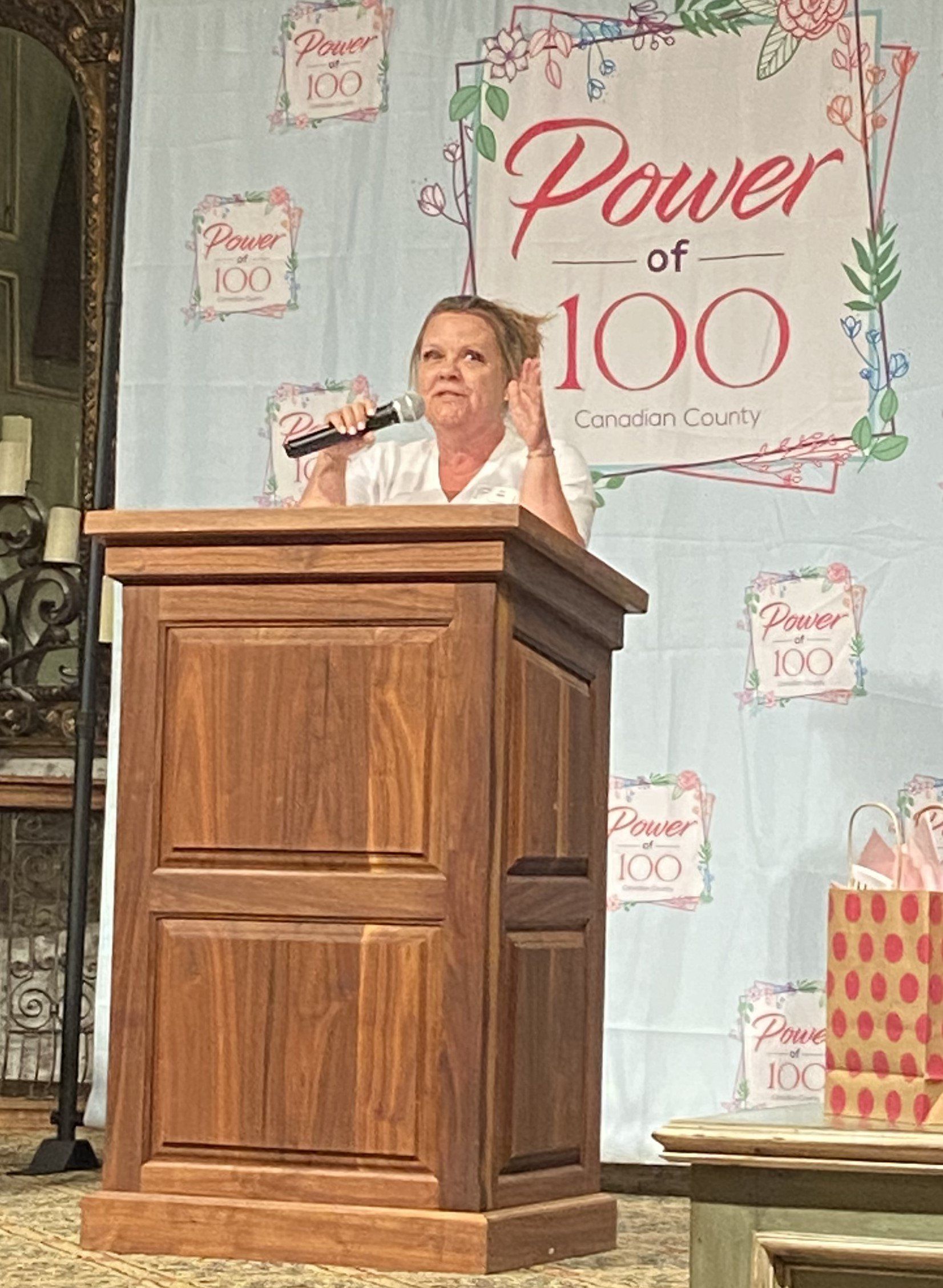 A woman is standing at a podium holding a microphone.
