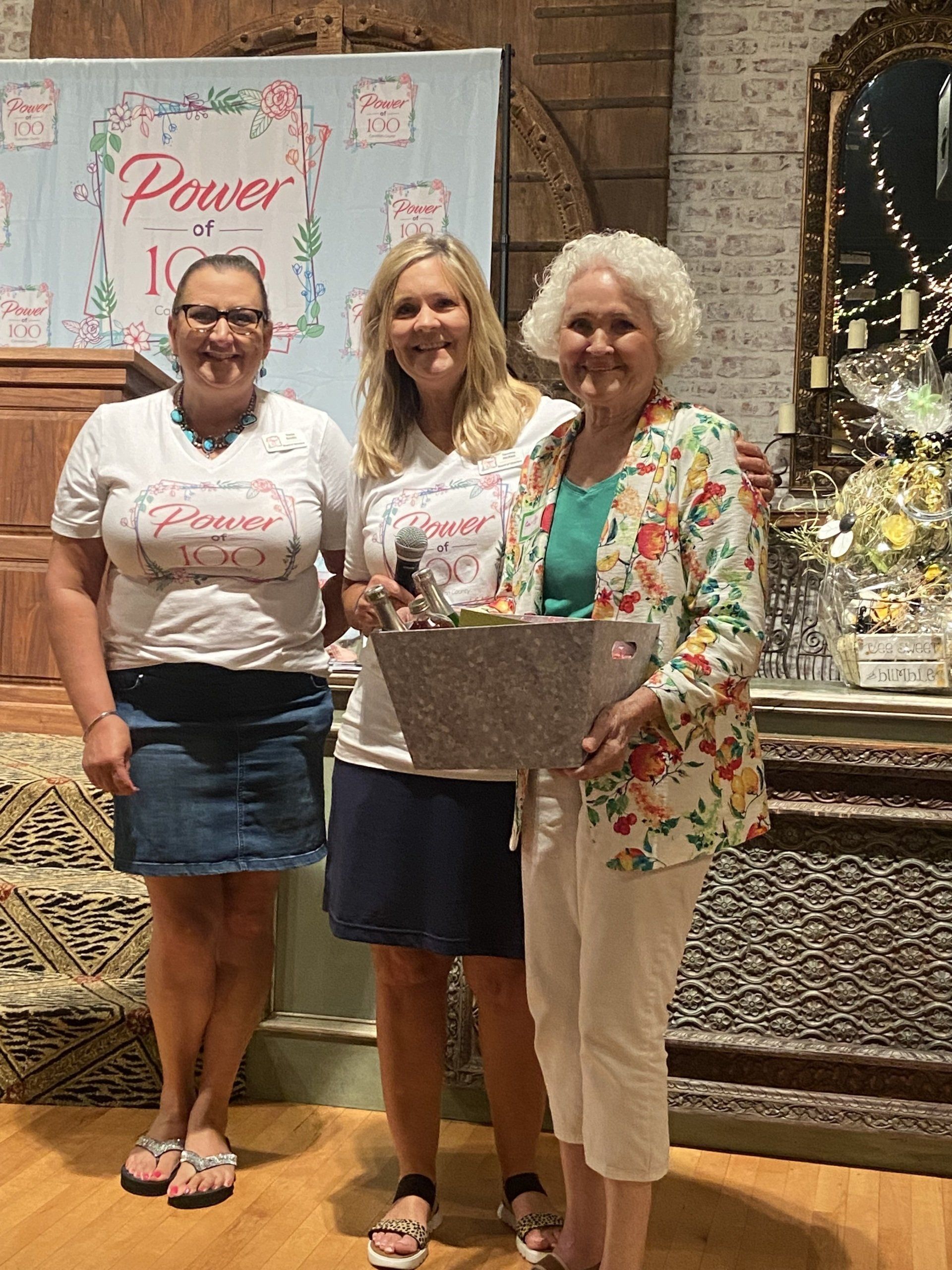 Three women are standing next to each other in front of a sign that says `` power ''.