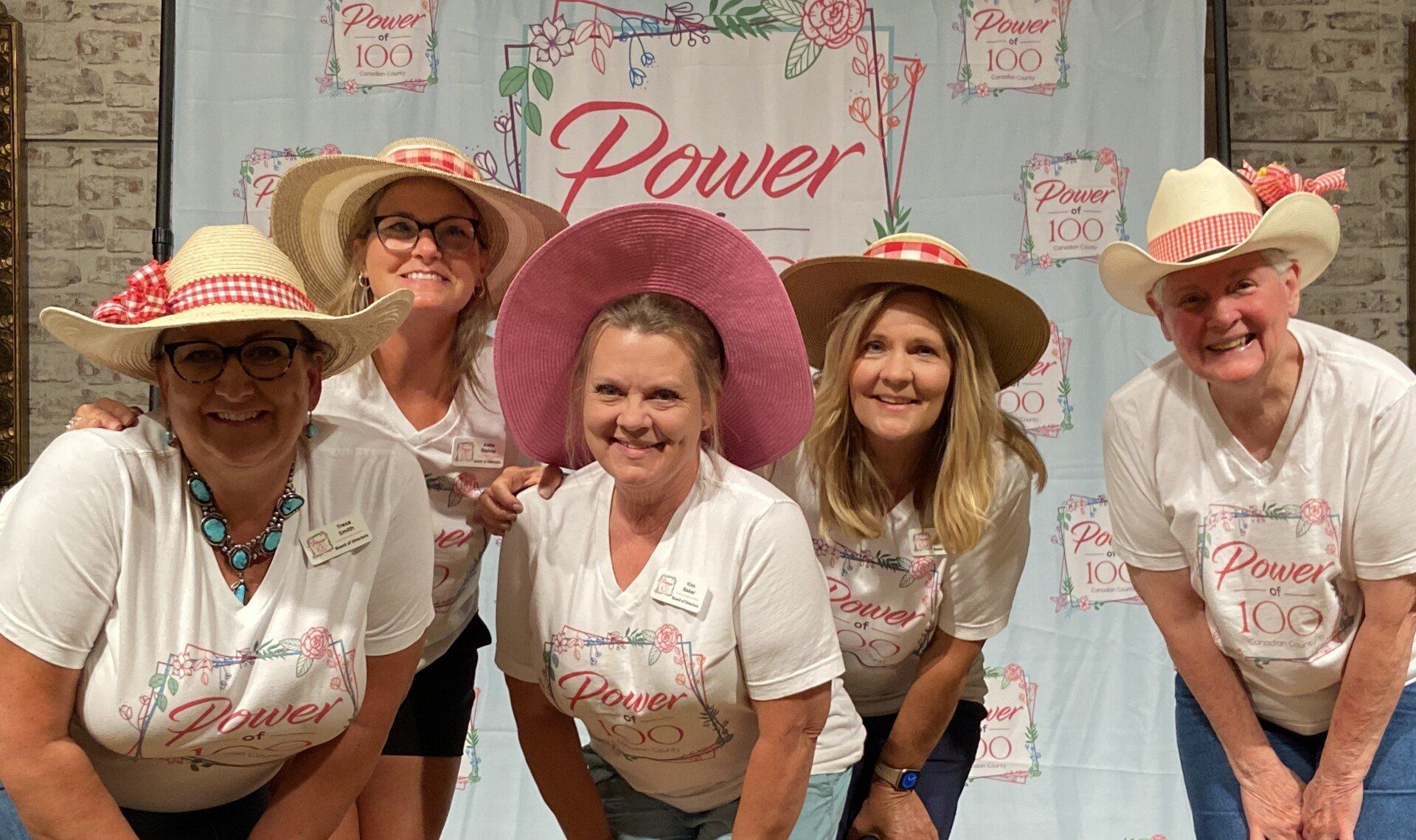 A group of women wearing cowboy hats and white shirts are posing for a picture.