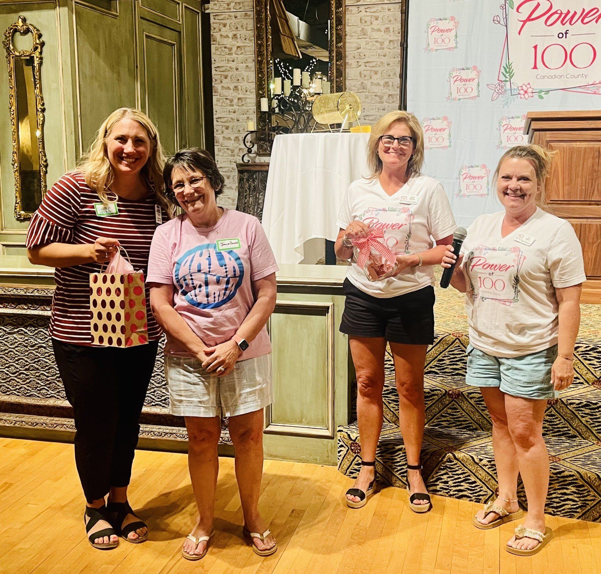 A group of women standing in front of a sign that says power 100