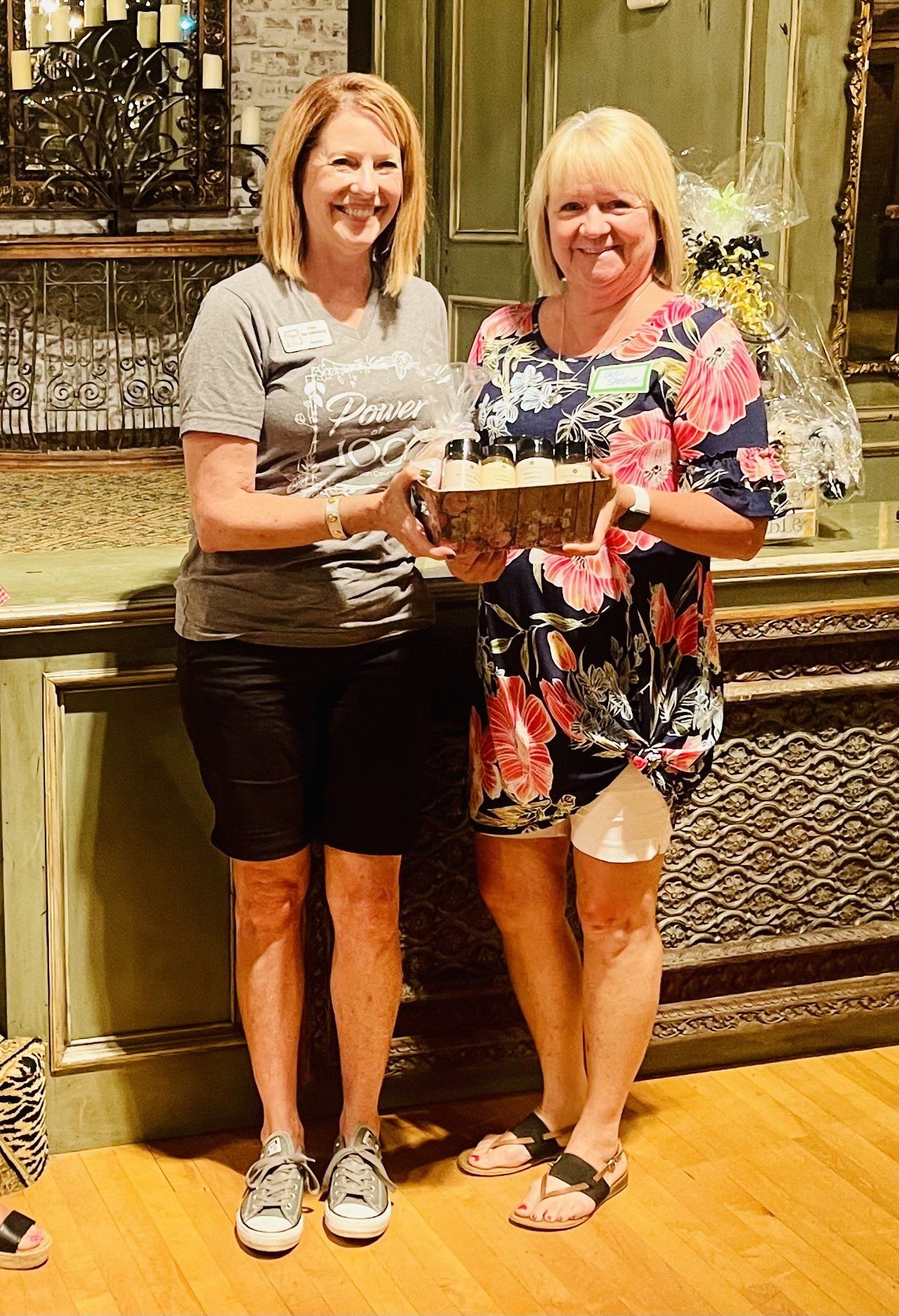 Two women are standing next to each other holding a cake.
