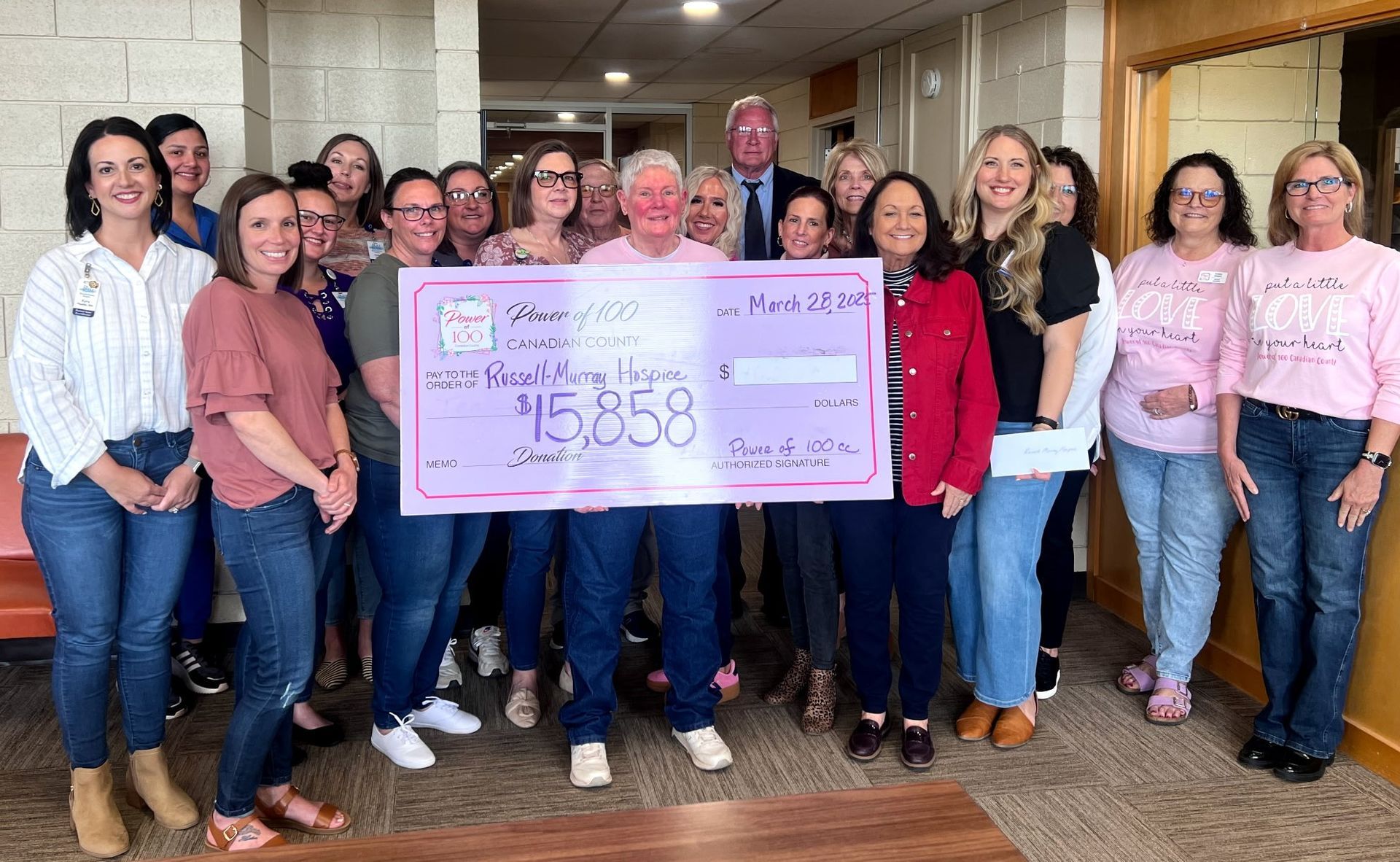 A group of women are posing for a picture while holding a large check.