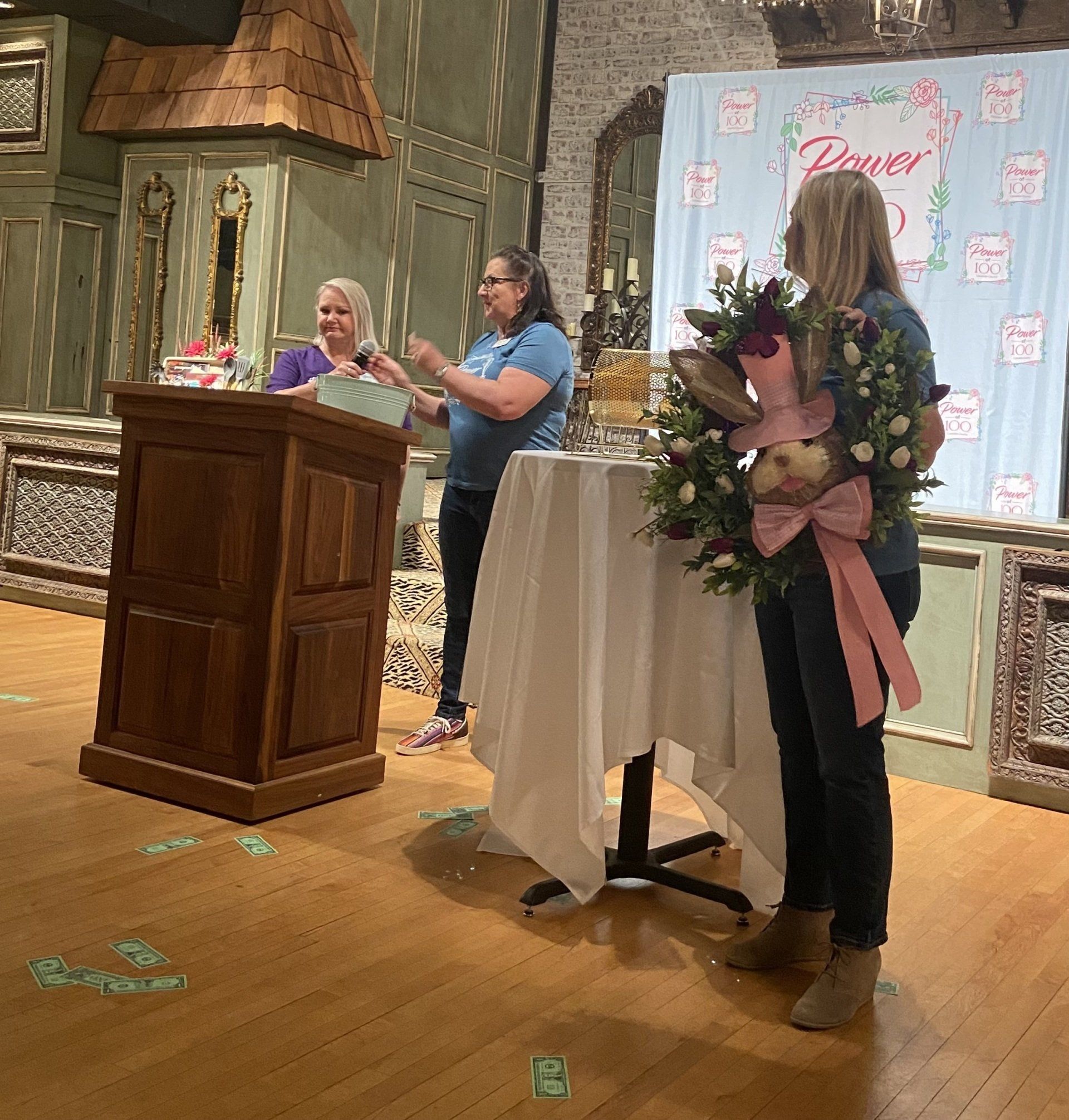 Two women are standing in front of a podium holding flowers.