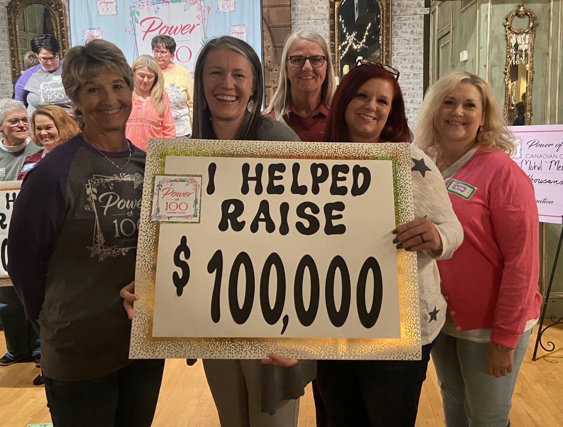 A group of women holding a sign that says i helped raise $ 100,000