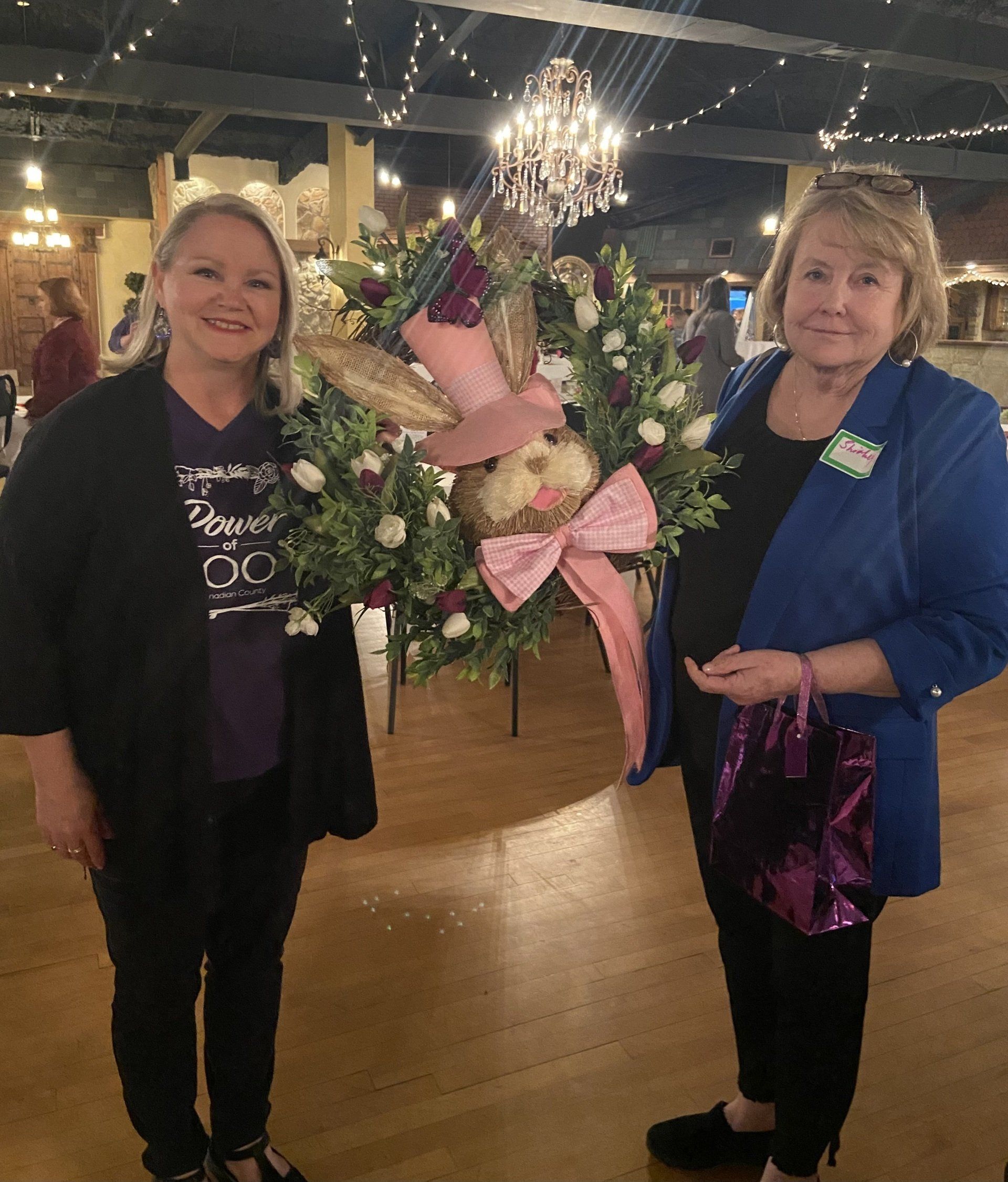 Two women standing next to each other in front of a bunny wreath