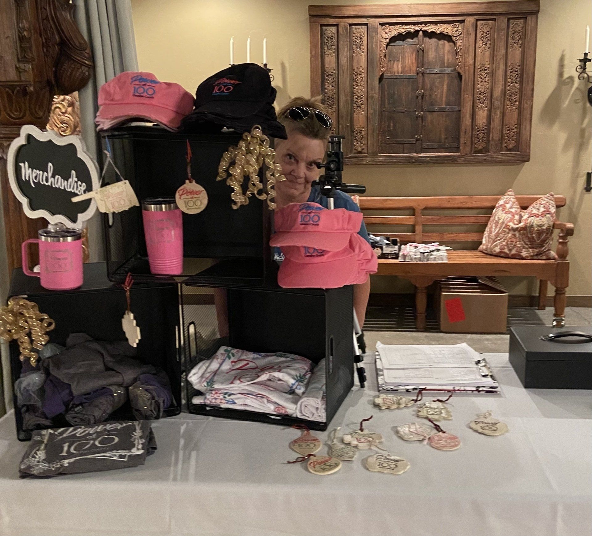 A woman is standing in front of a display of pink hats.