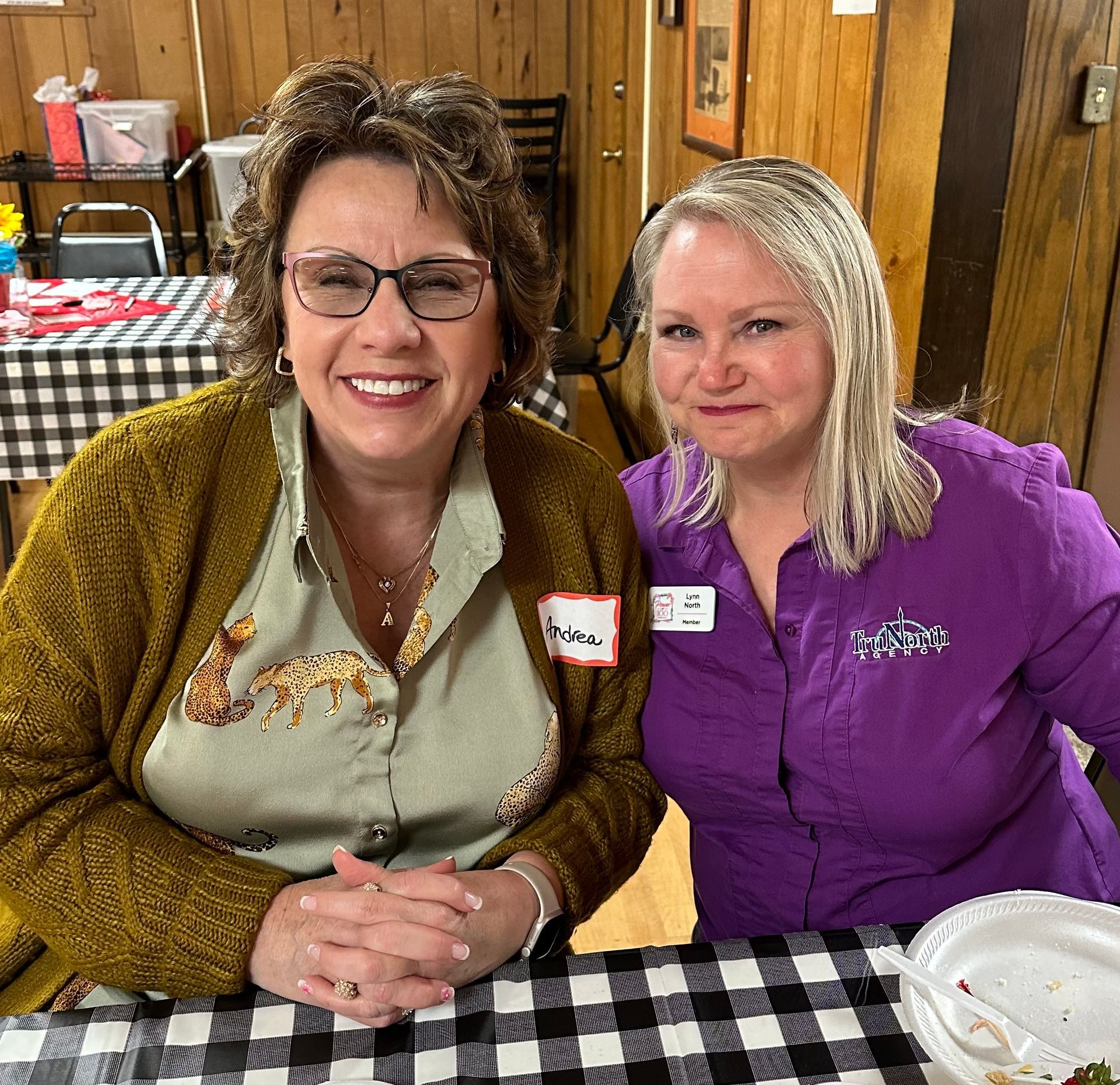 Two women are posing for a picture while sitting at a table