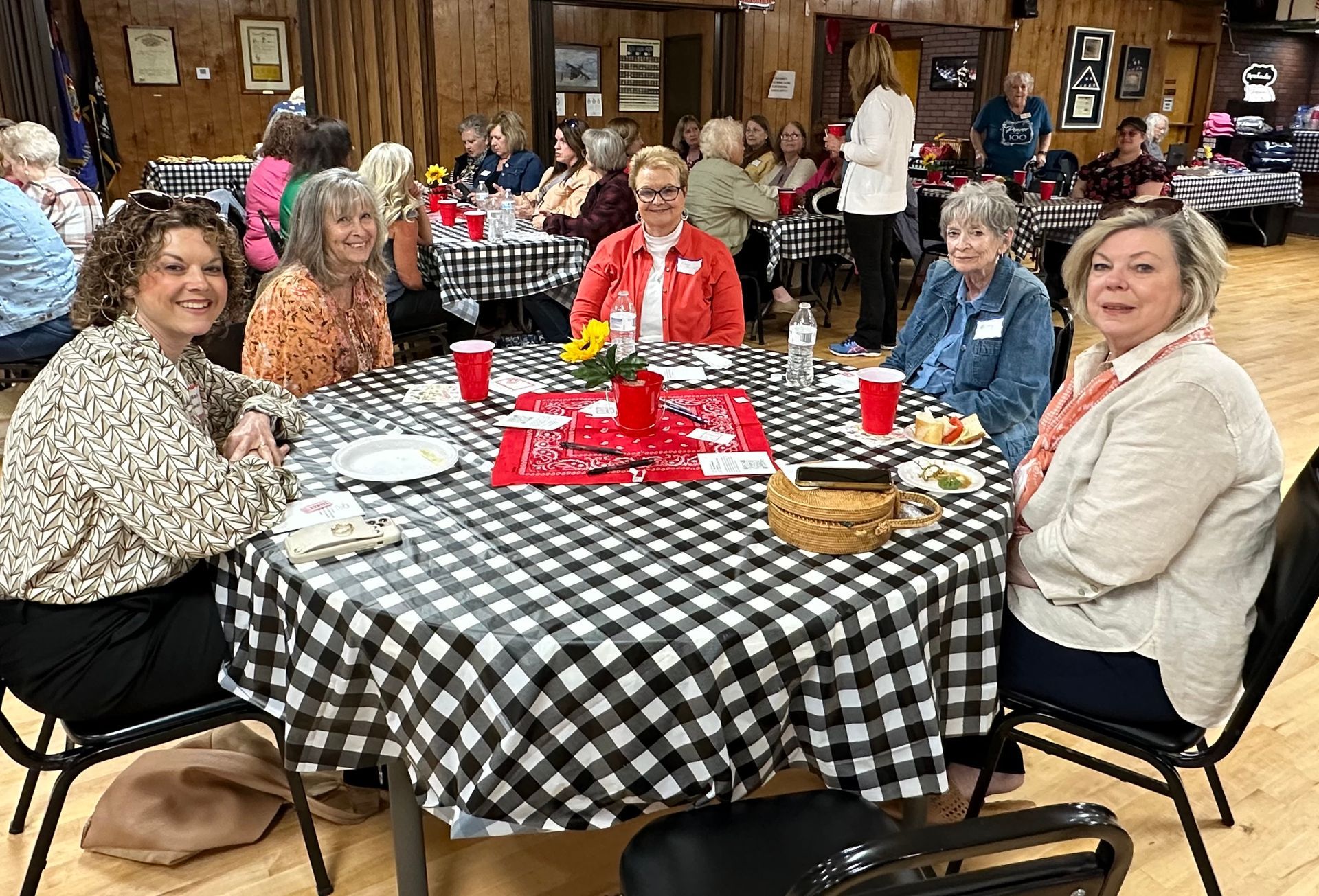 A group of women are sitting at a table with a checkered tablecloth.
