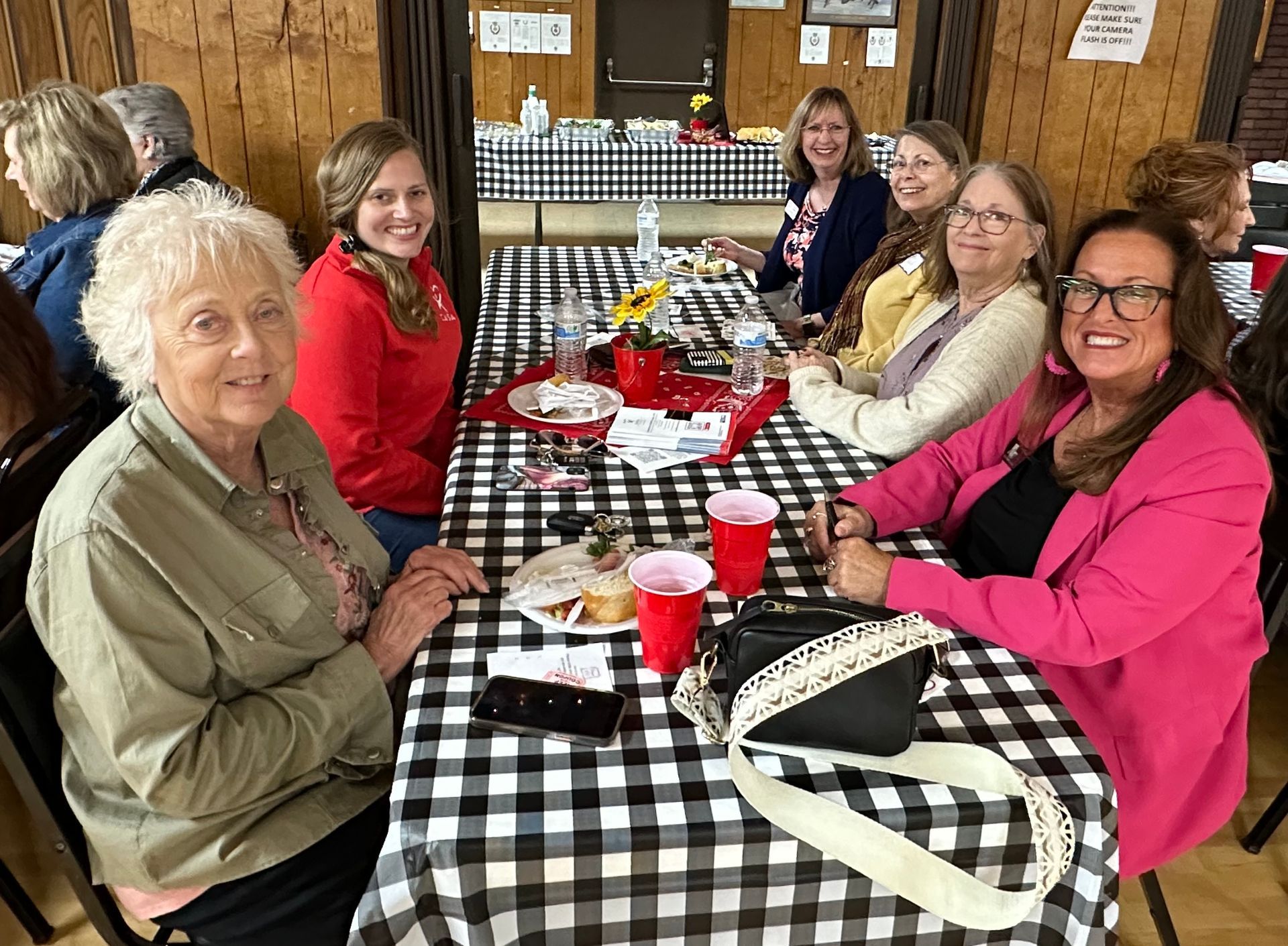 A group of women are sitting at a table with a checkered tablecloth.