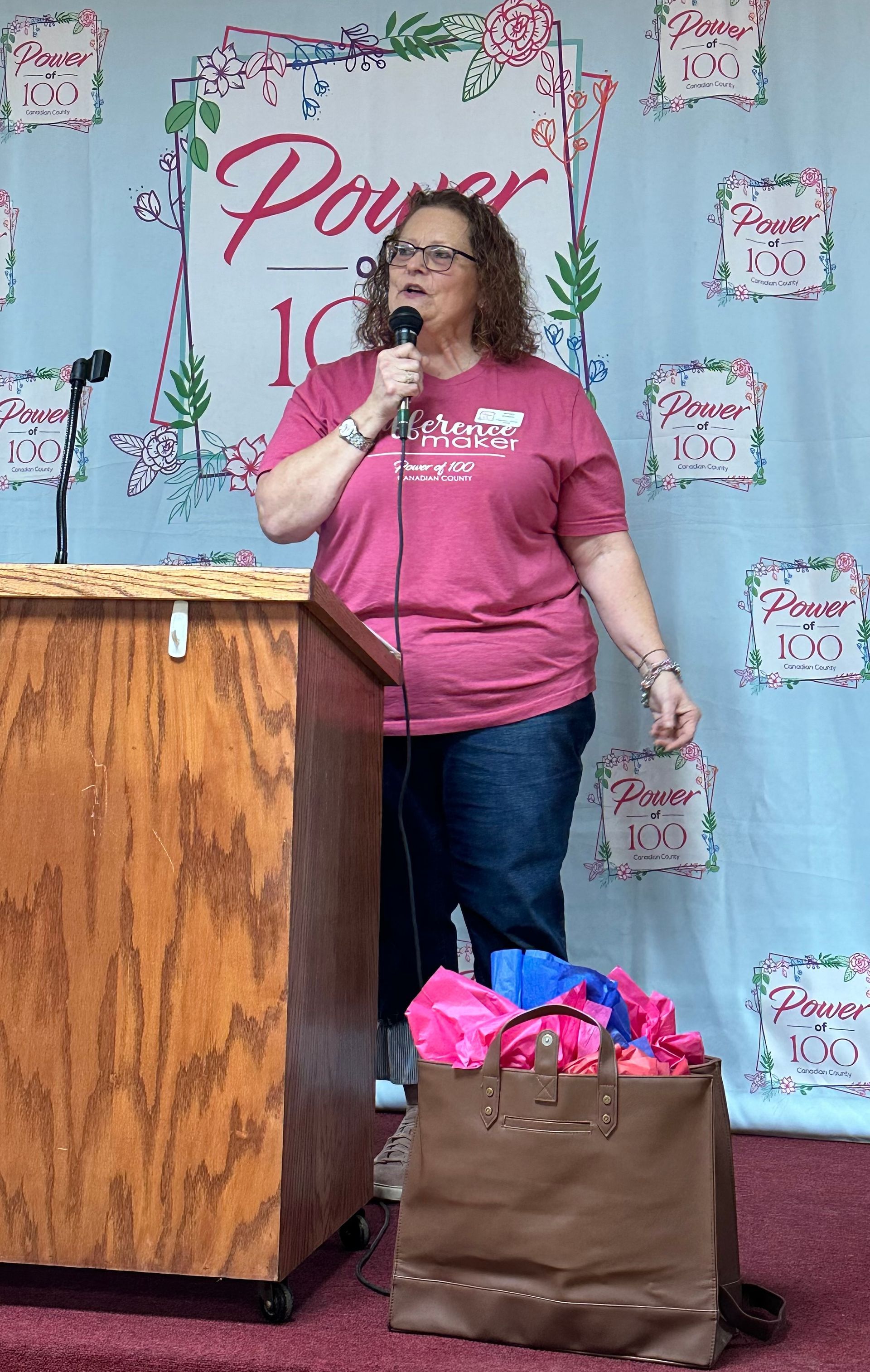 A woman is standing at a podium holding a microphone.