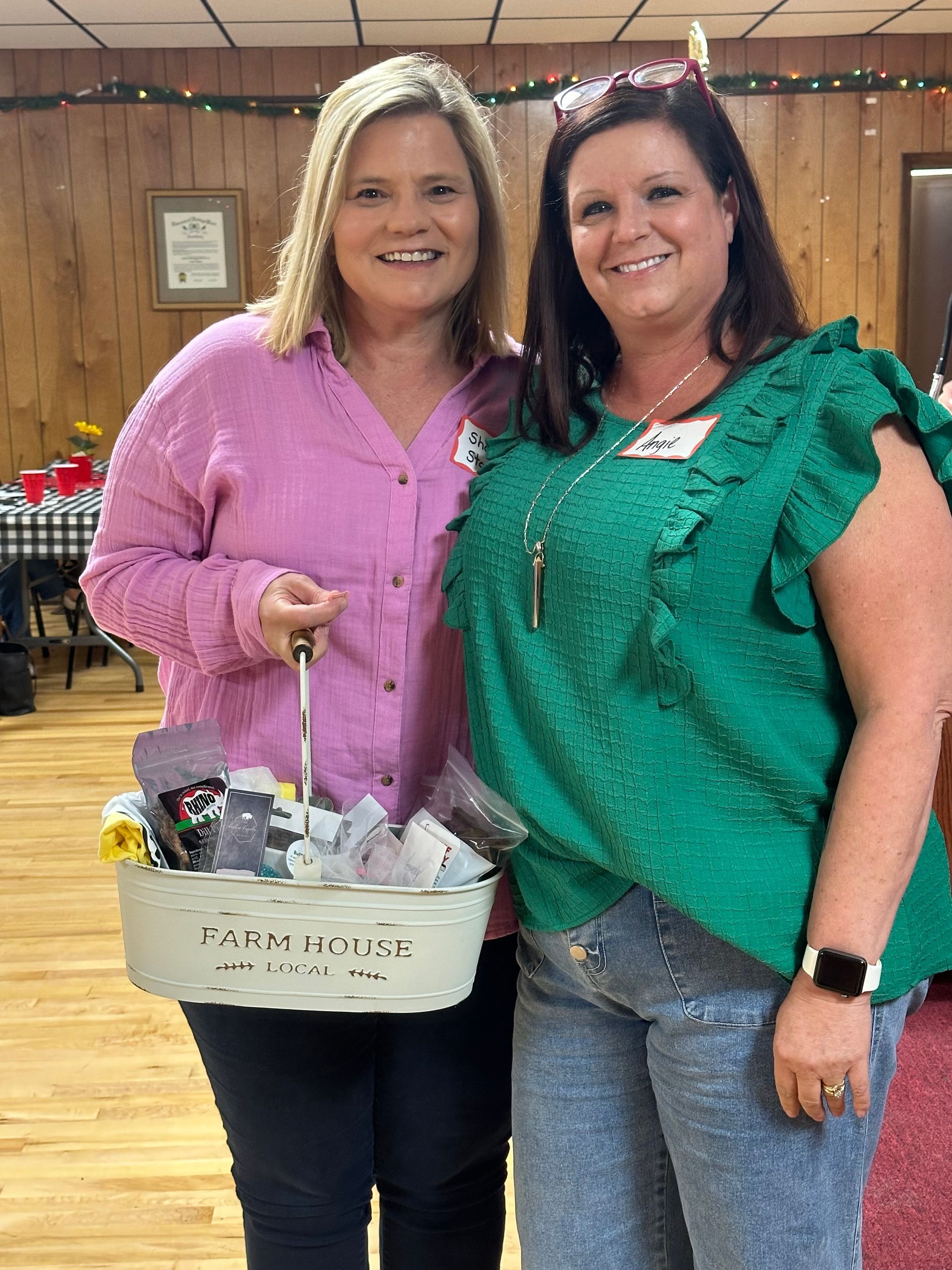Two women are posing for a picture while one of them is holding a basket.