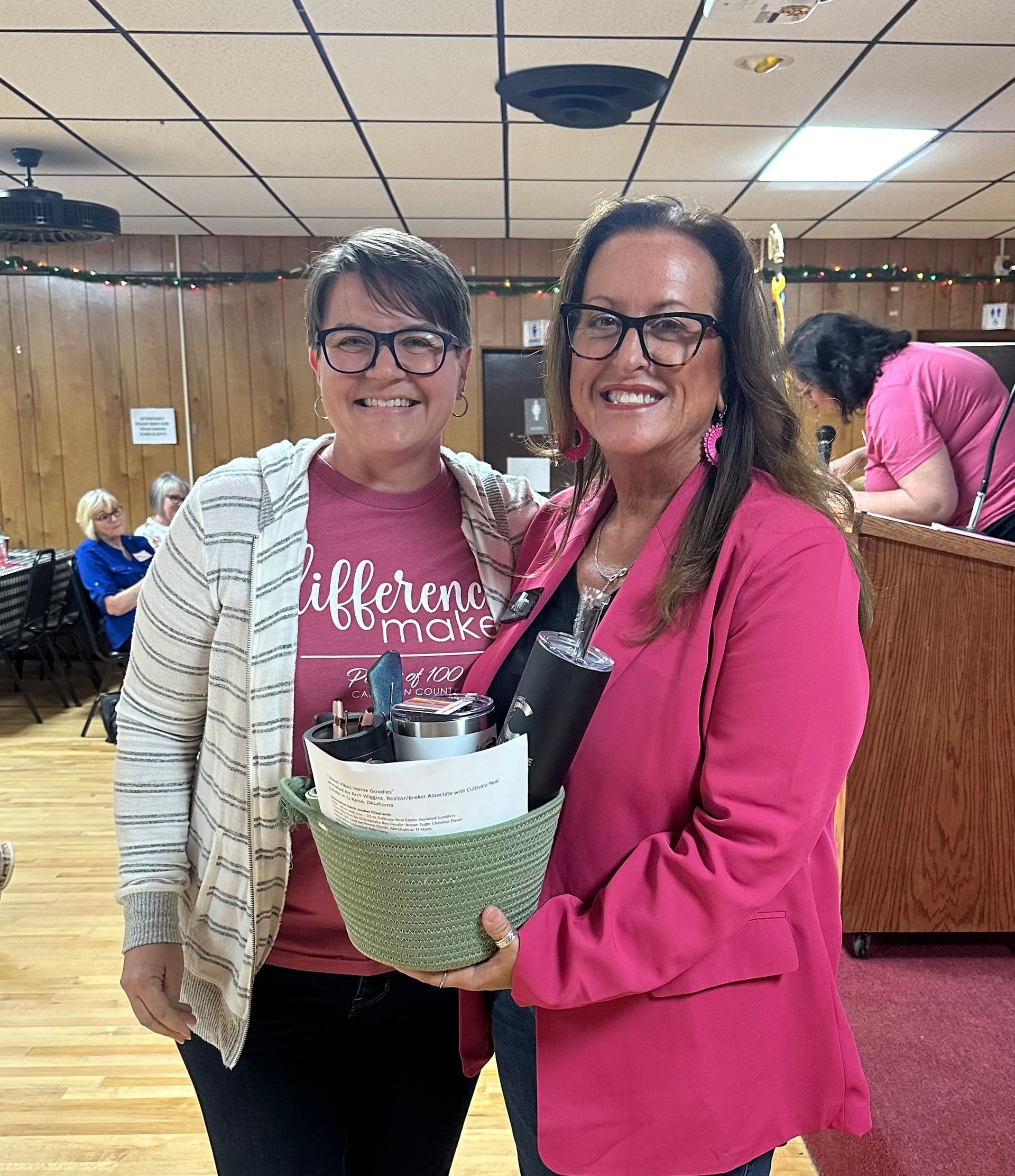 Two women are standing next to each other in a room holding baskets.