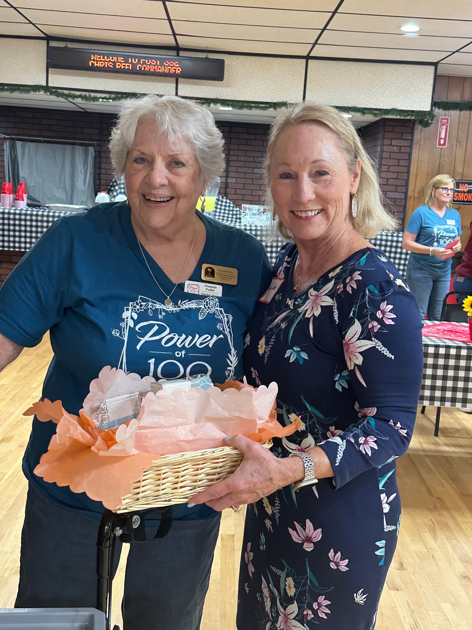 Two women are standing next to each other and one is holding a basket.