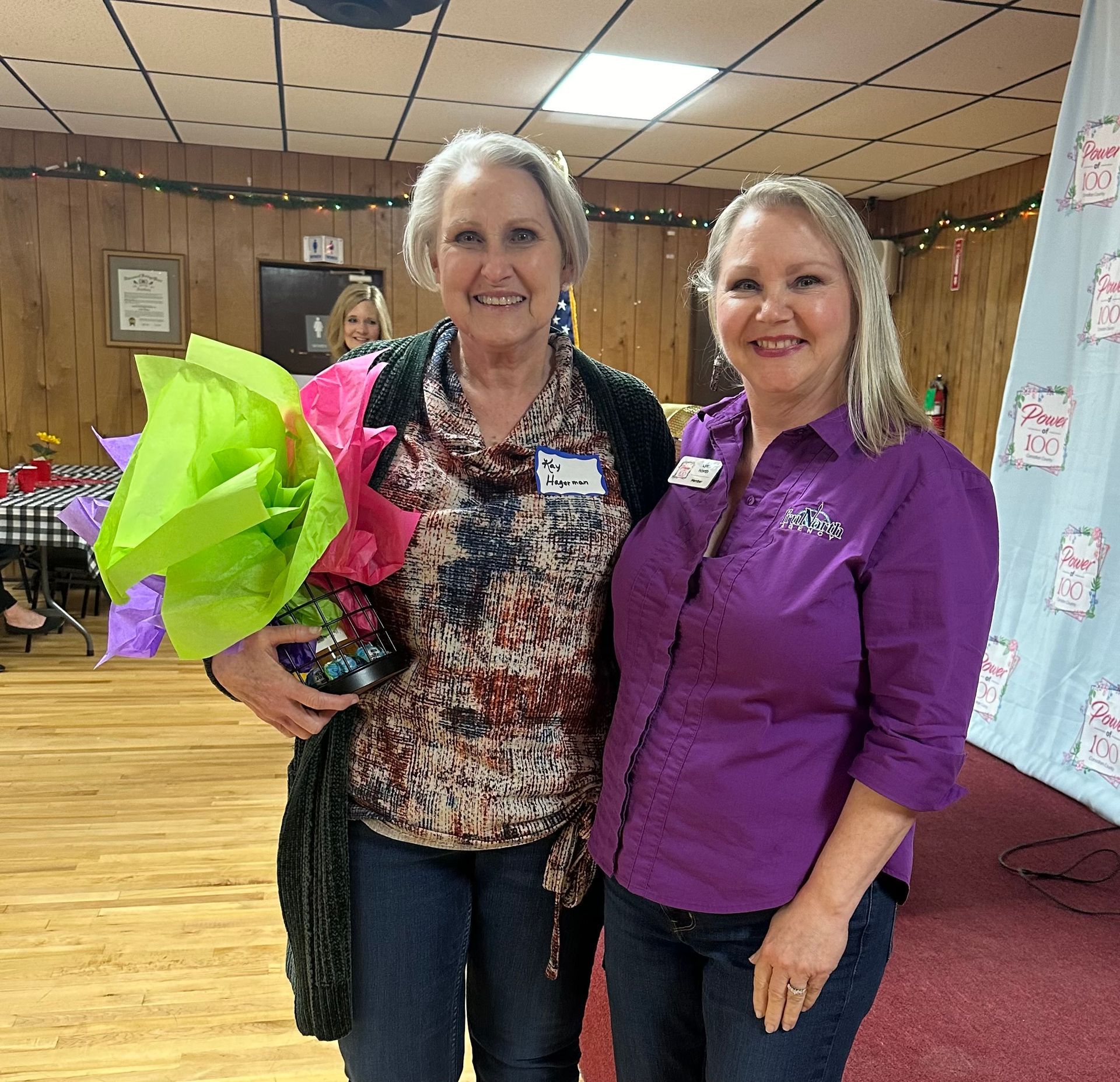 A woman in a purple shirt stands next to another woman