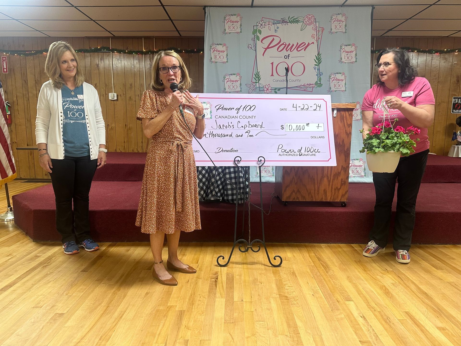 Three women are standing in front of a large check.