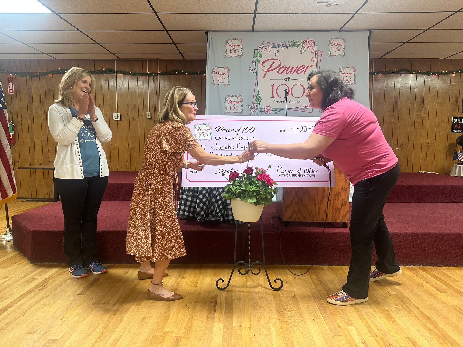 A woman is giving a check to another woman on a stage.