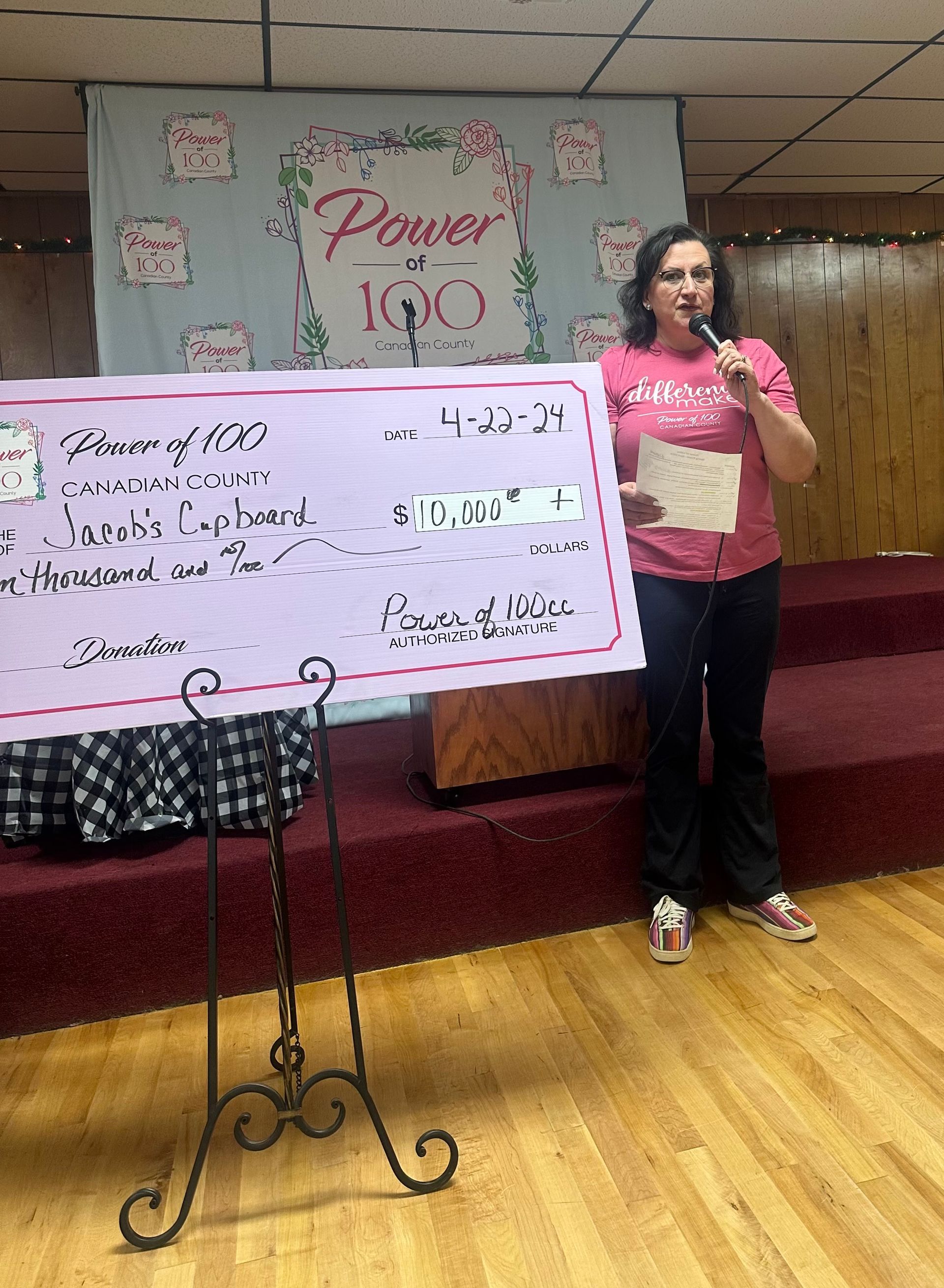 A woman is holding a microphone while standing in front of a large check.