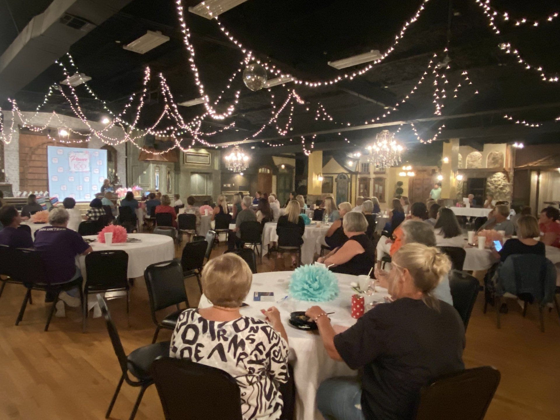 A large group of people are sitting at tables in a large room.