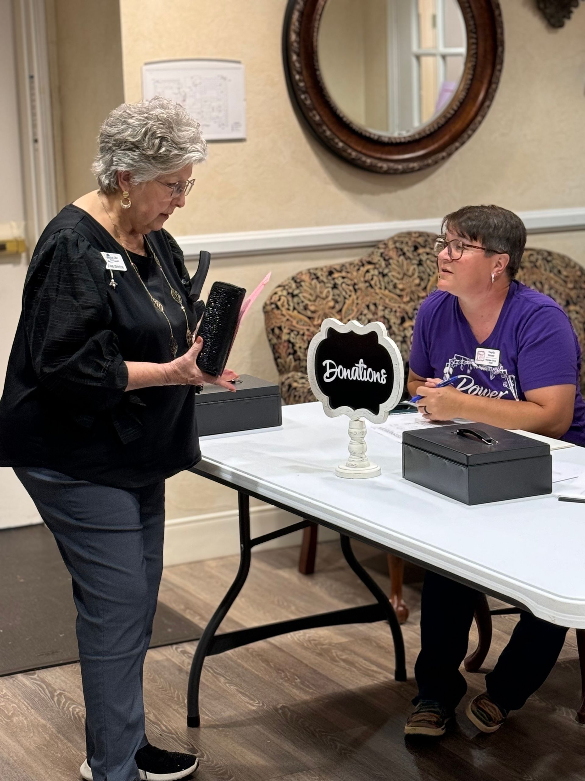 Two women are sitting at a table talking to each other.