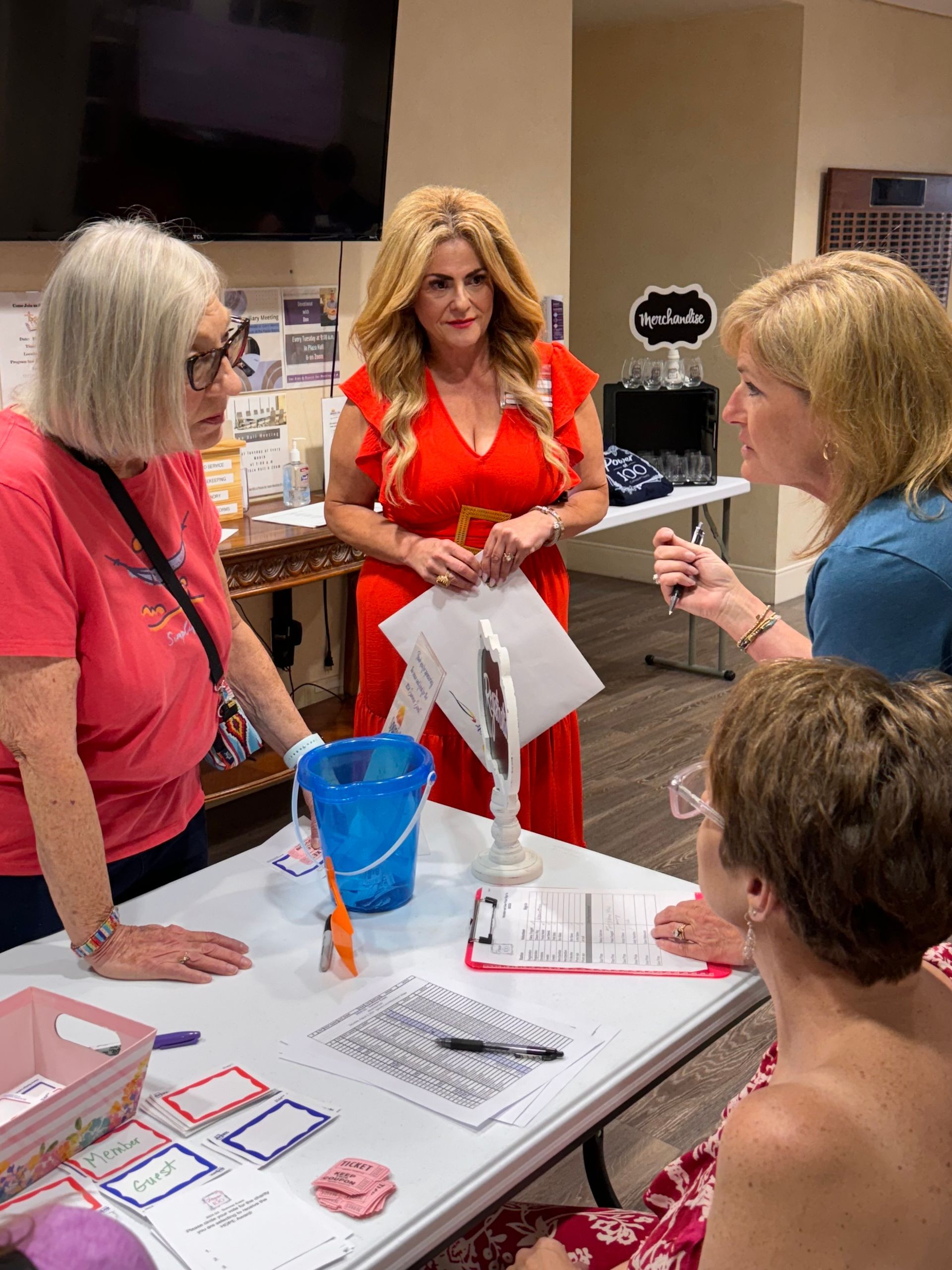 A group of women are sitting around a table talking to each other.