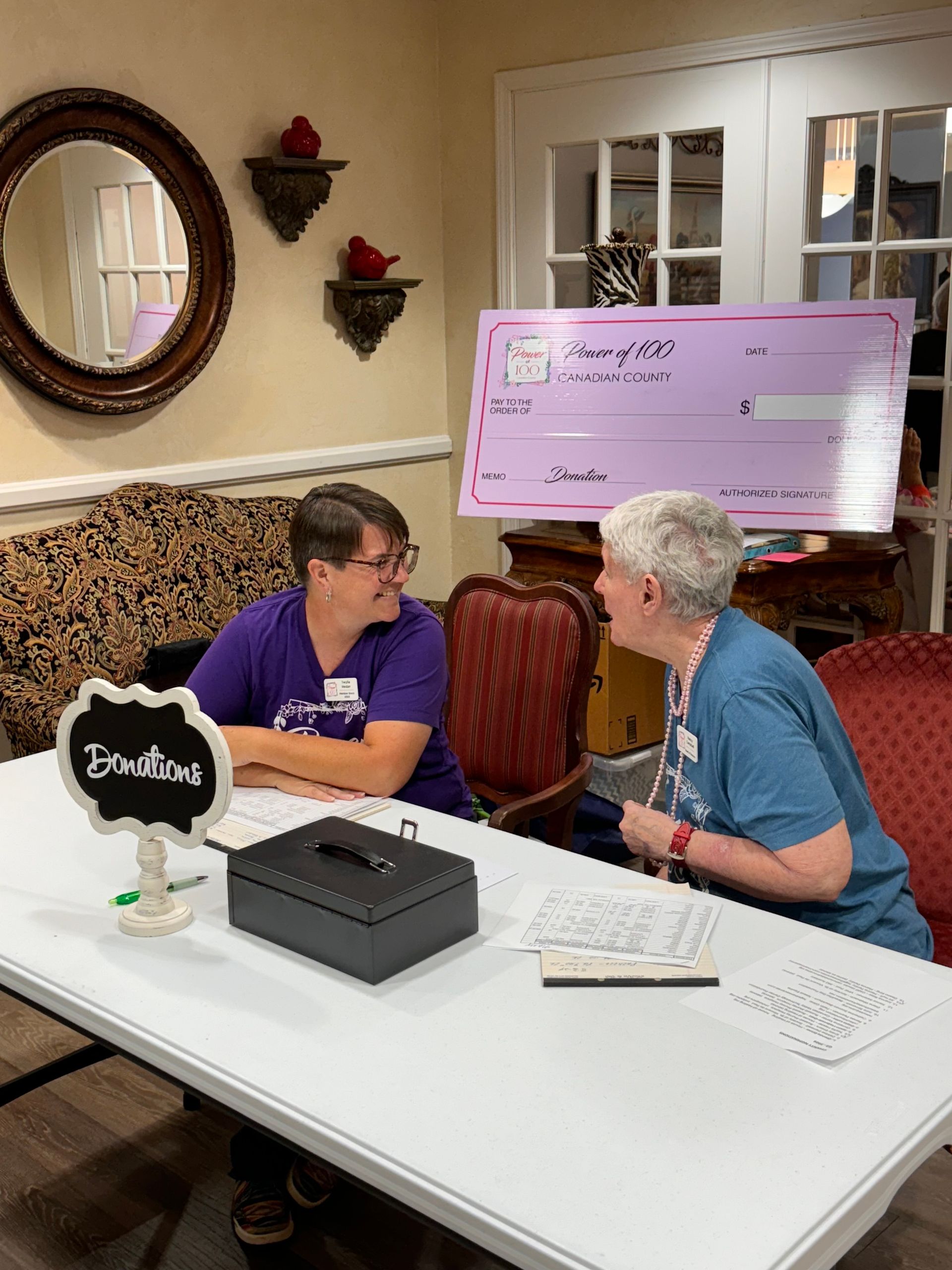 Two women are sitting at a table talking to each other.