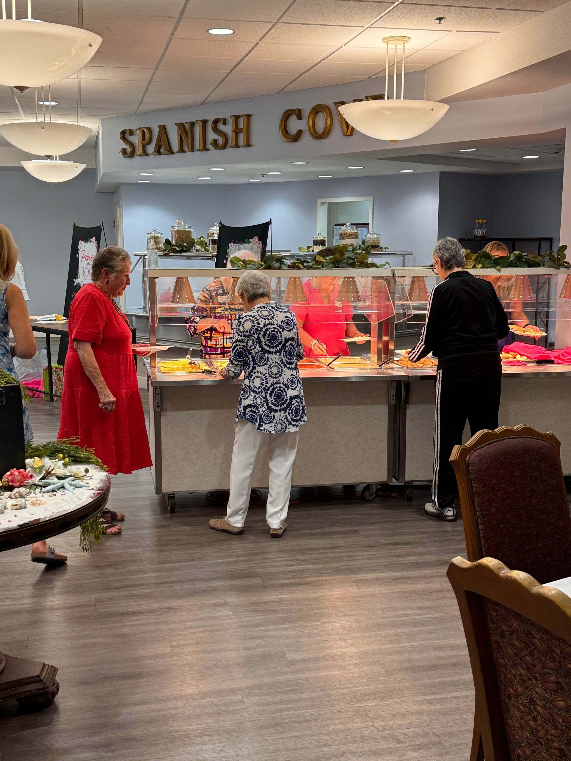 A group of people are standing around a buffet line in a restaurant.