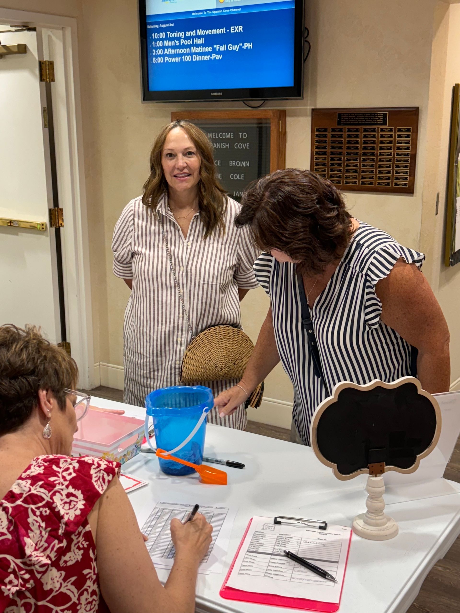Two women are standing next to each other at a table.