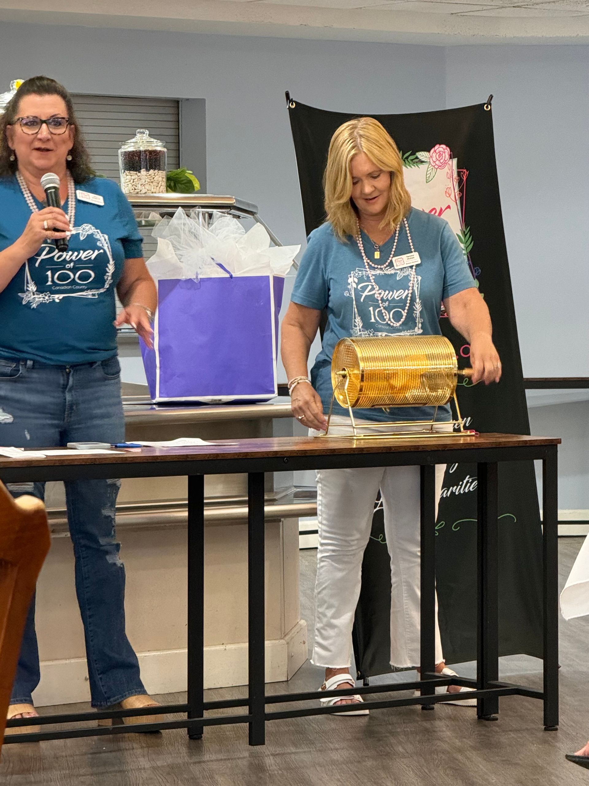 A woman in a blue shirt that says forever 100 is holding a microphone