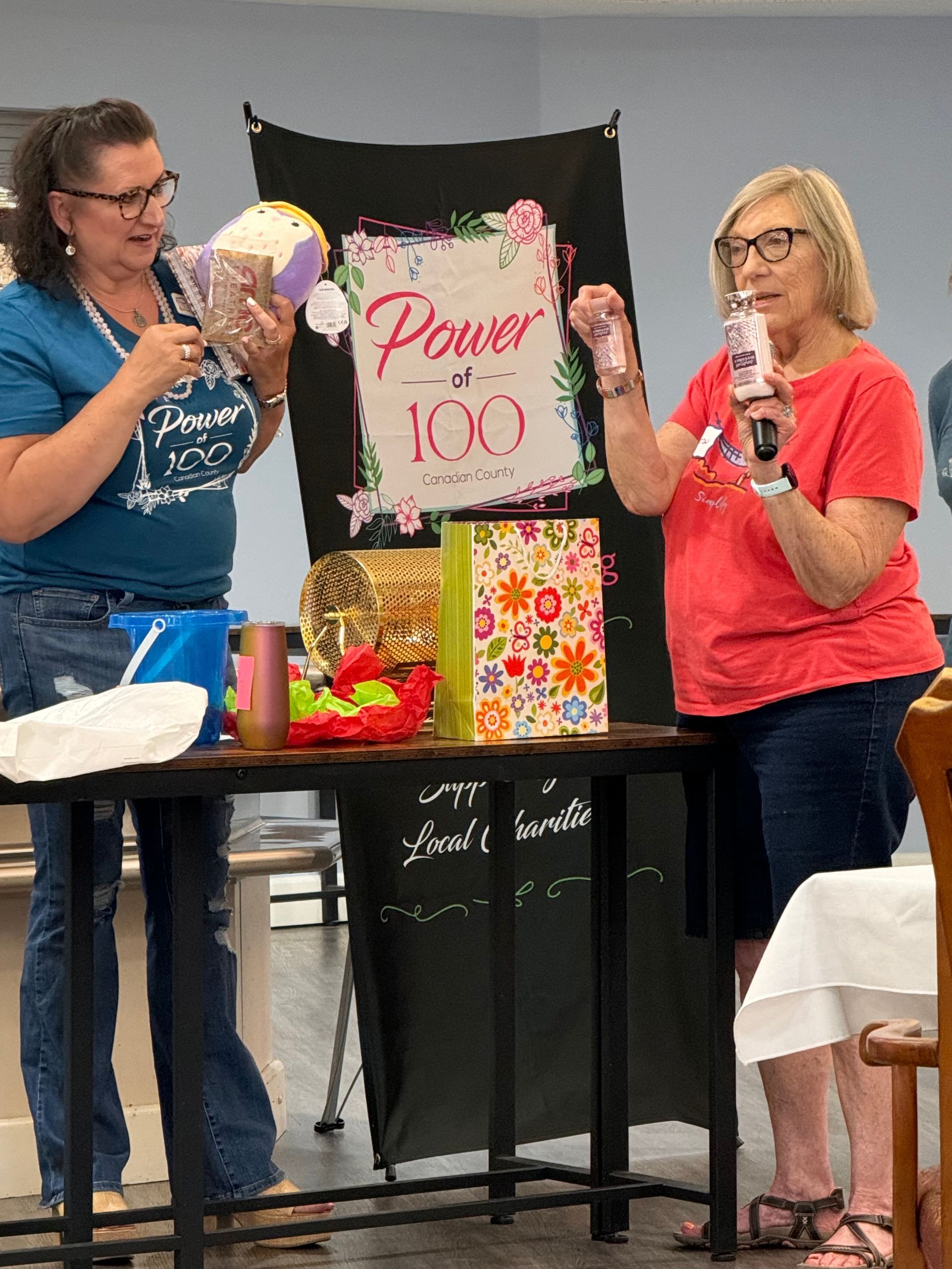 Two women are standing in front of a table with a sign that says power of 100