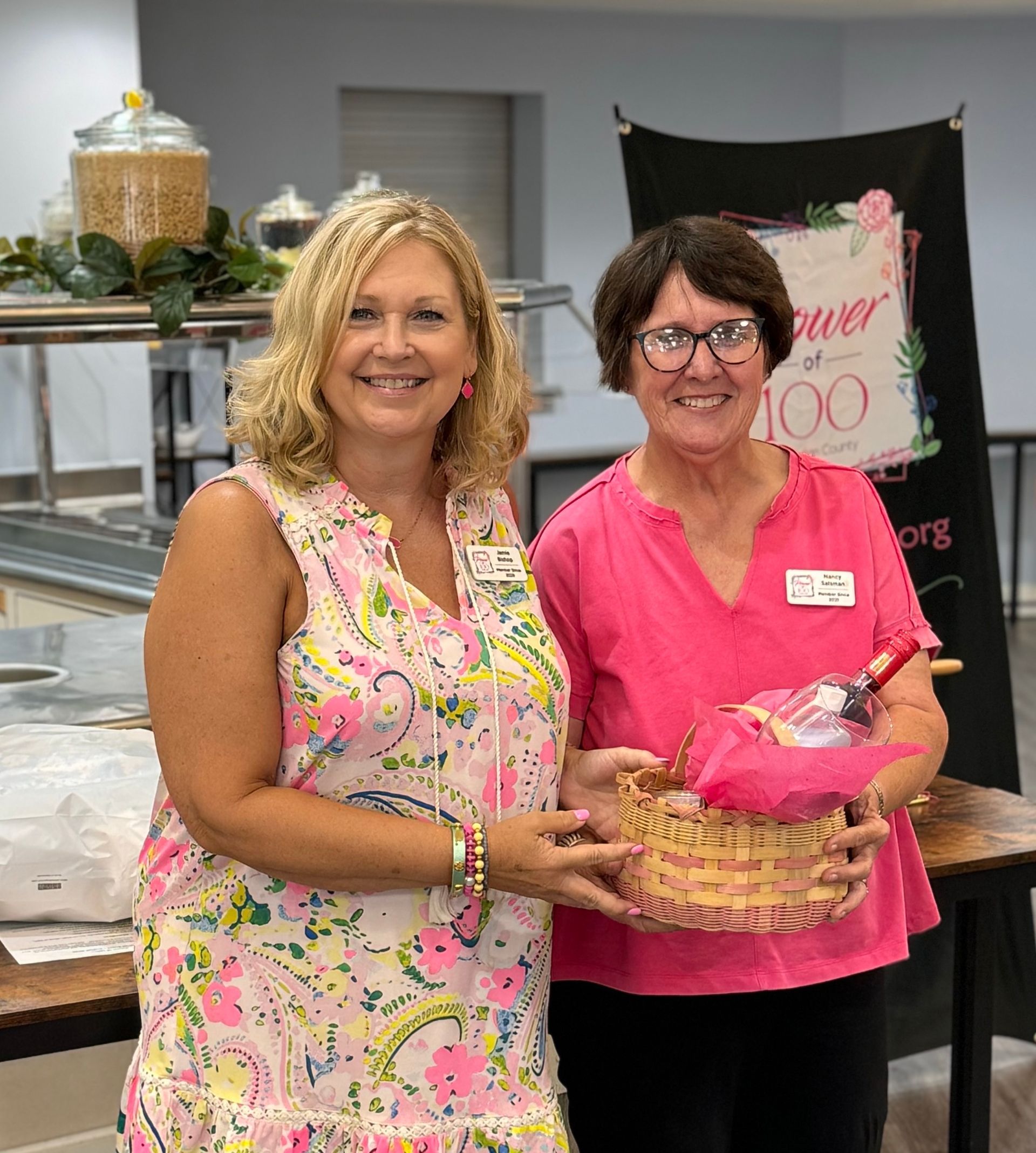 Two women are standing next to each other holding baskets and smiling.