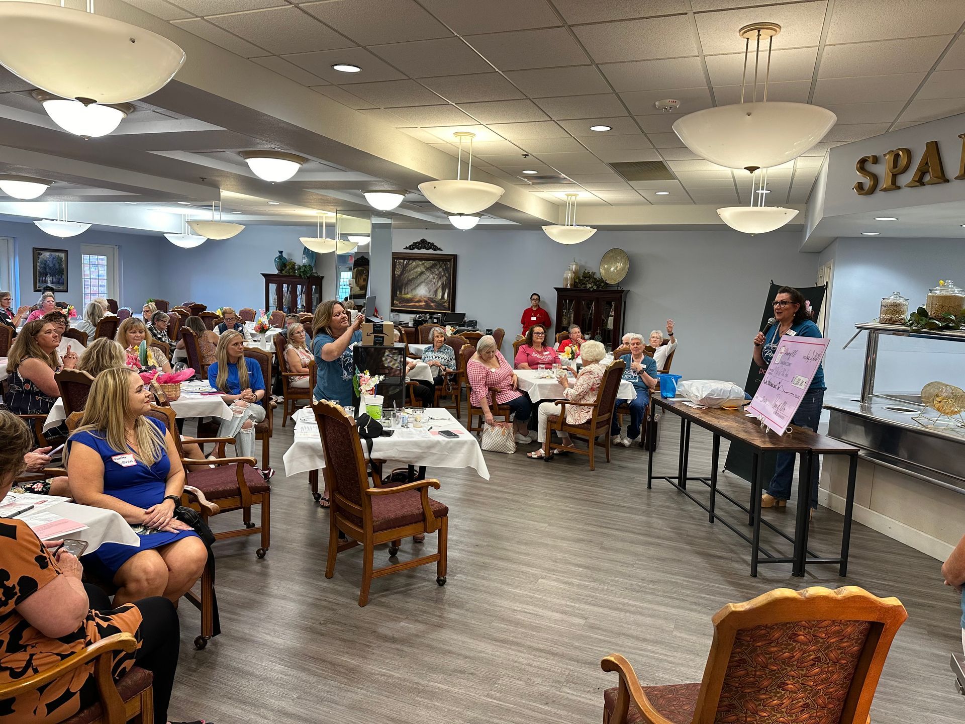 A large room filled with people sitting at tables and chairs.
