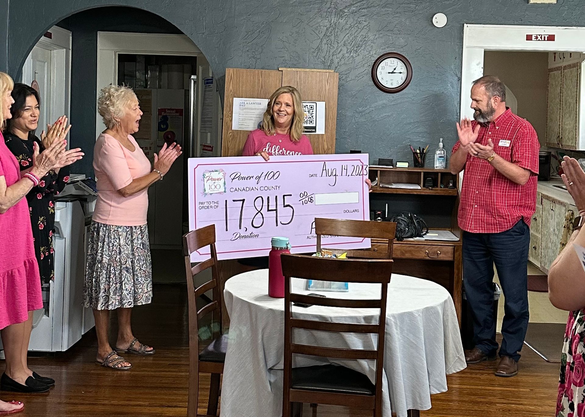 A group of people standing around a table holding a large check.