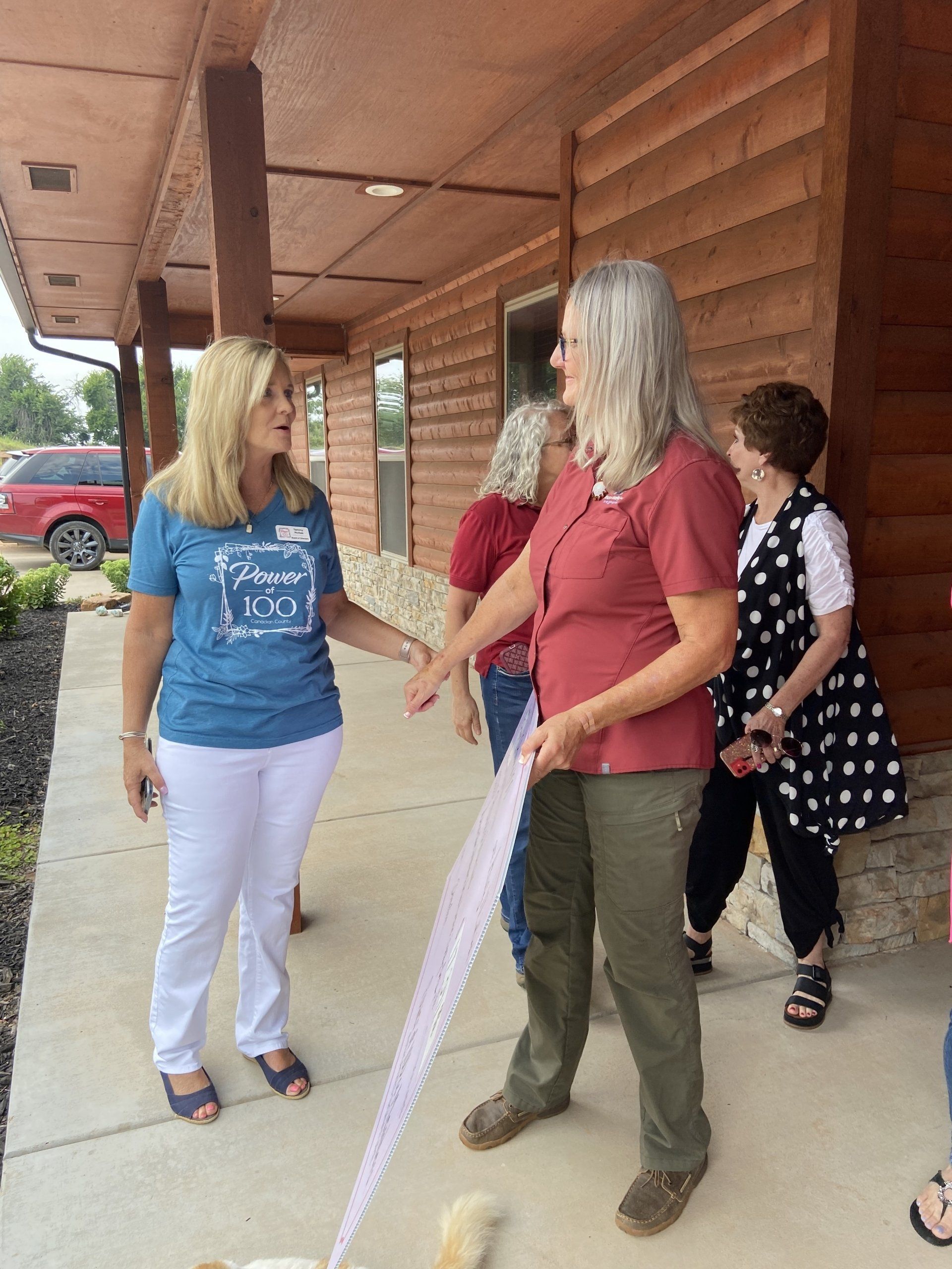 A group of women are standing outside of a building talking to each other.