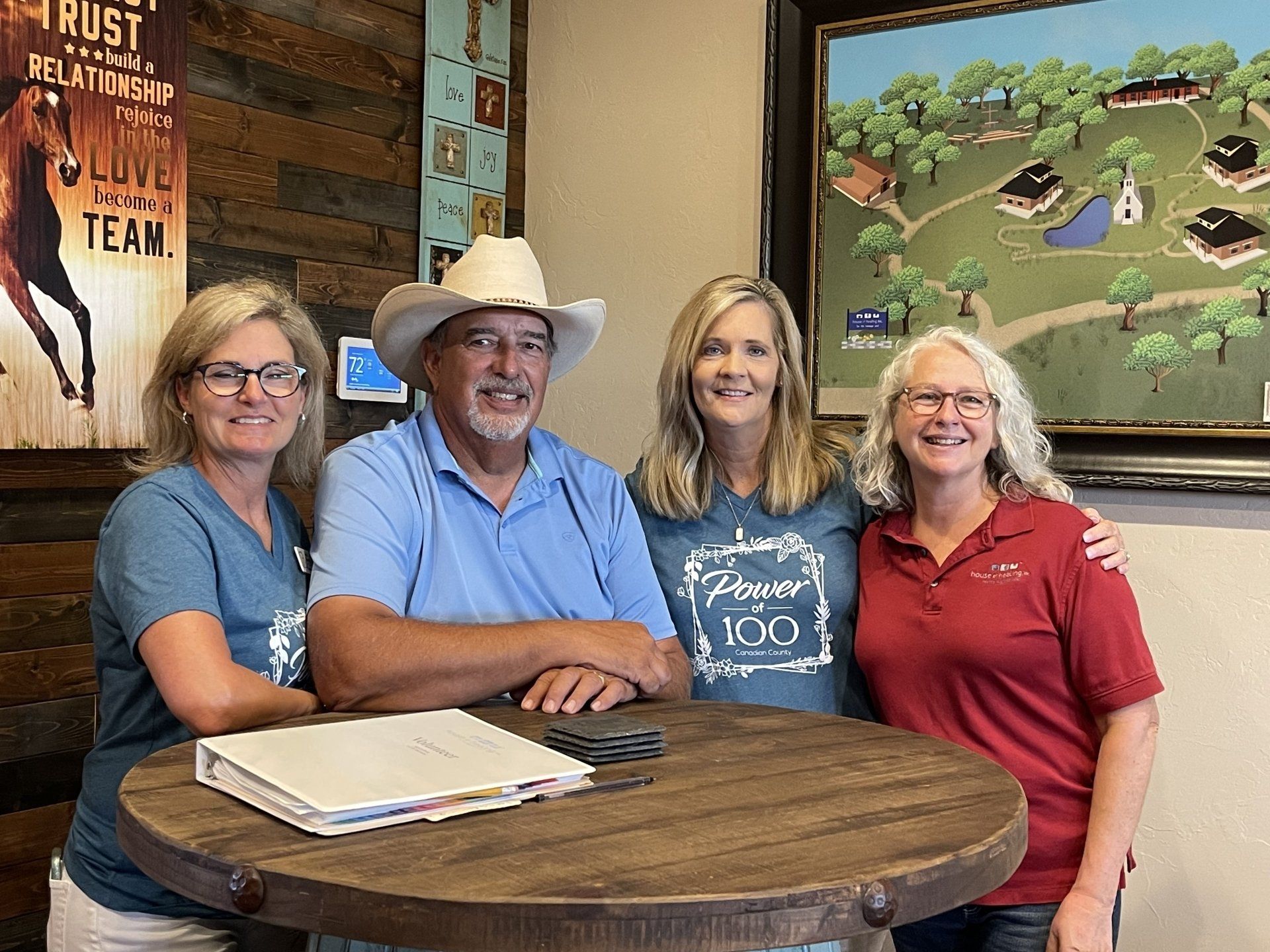 A group of people are posing for a picture while sitting around a table.