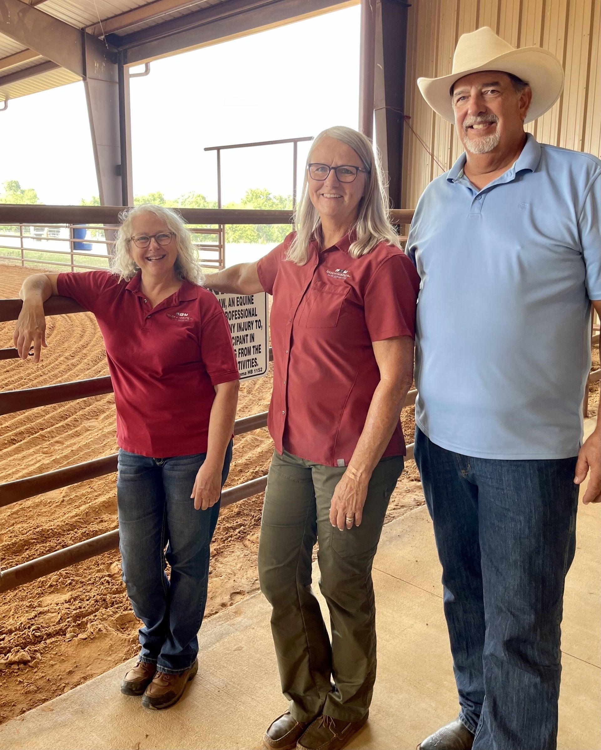A man and two women are standing next to each other in a barn.
