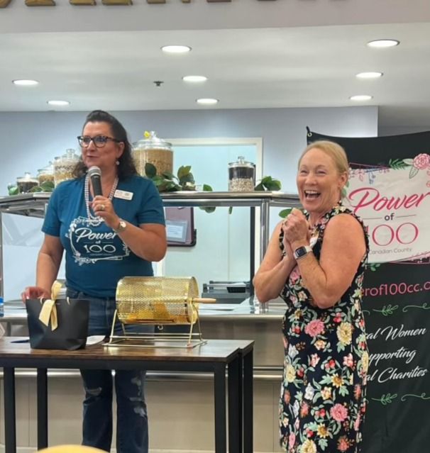 Two women standing in front of a sign that says power 100
