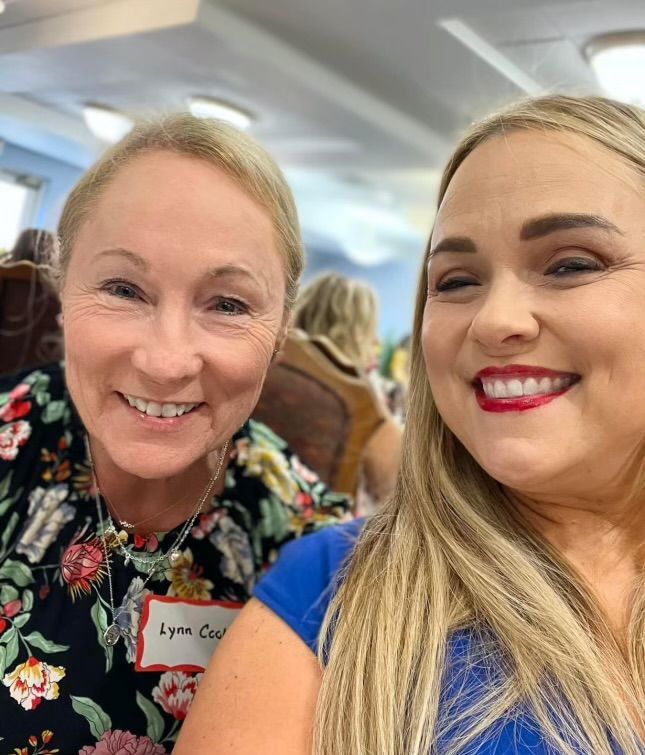 Two women are posing for a picture together and smiling for the camera.