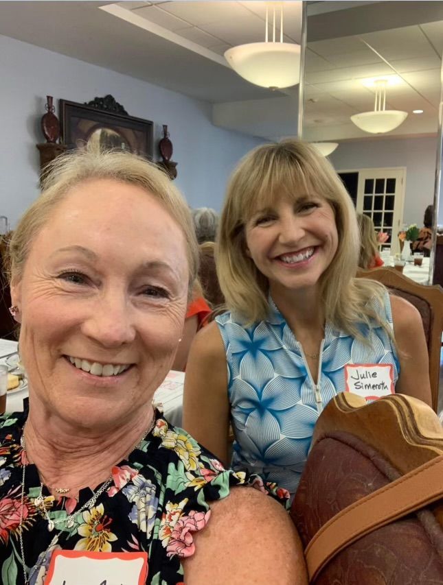Two women are posing for a picture in a room and smiling.