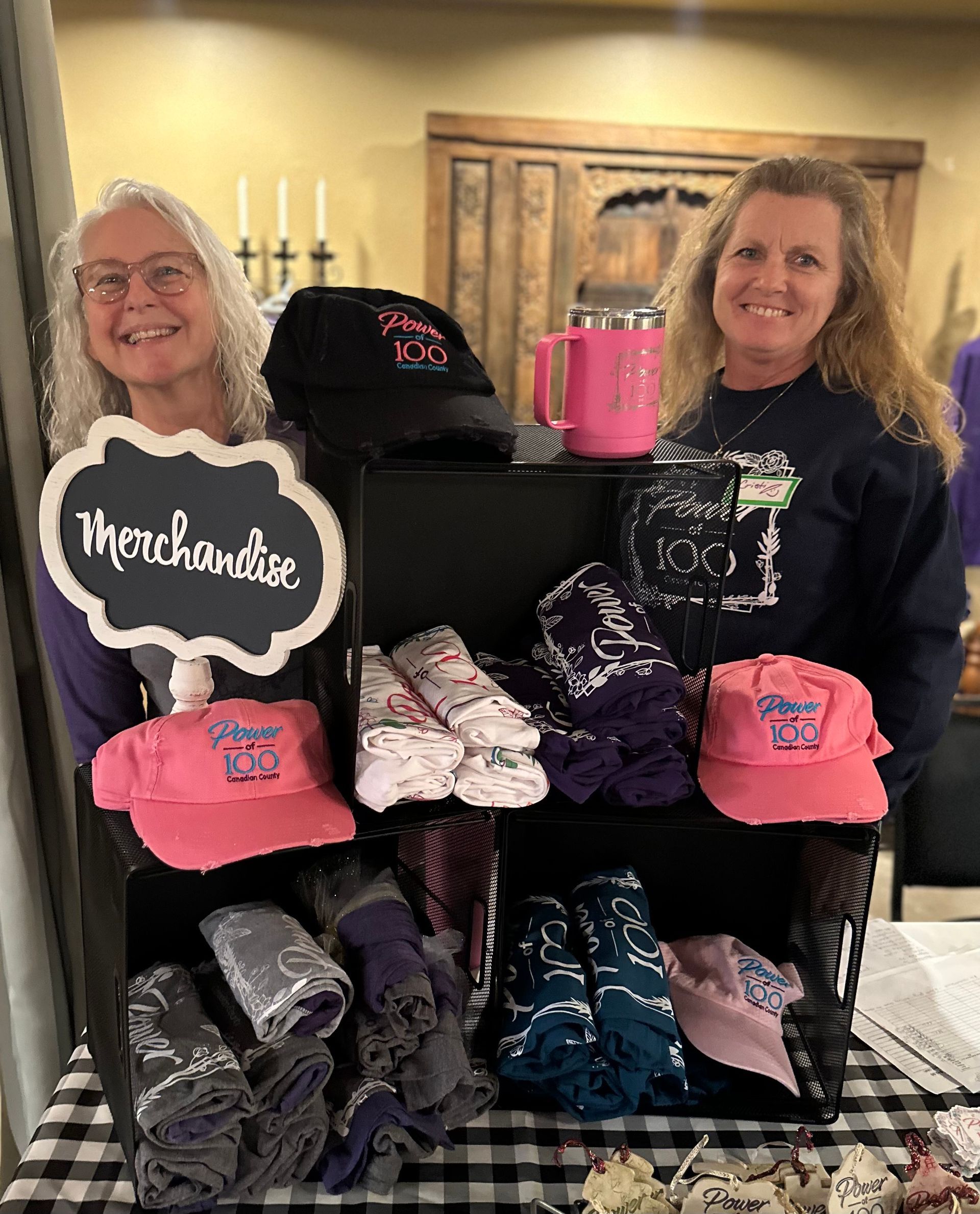 Two women are standing in front of a display of merchandise.