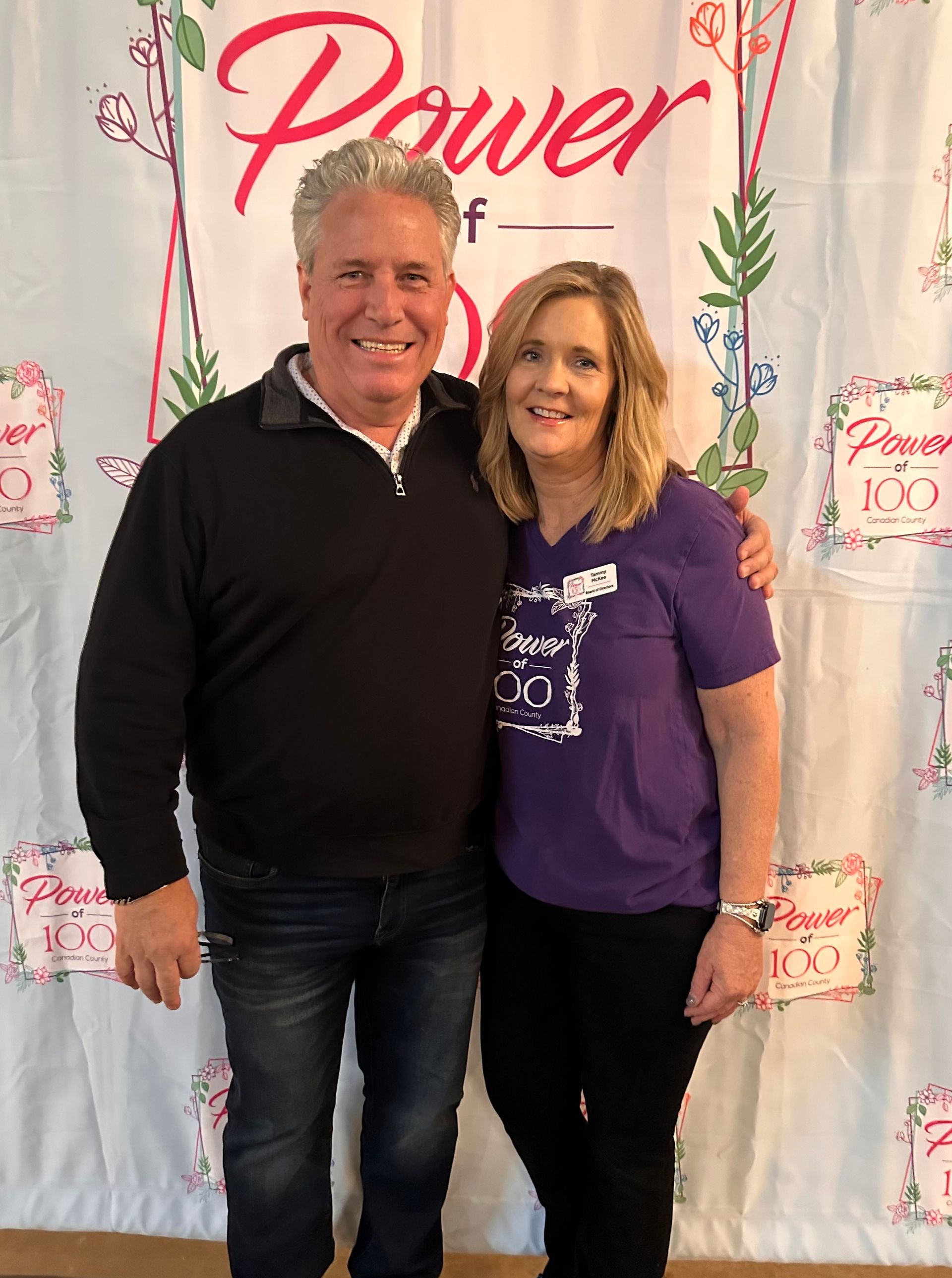 A man and a woman are posing for a picture in front of a sign that says power.