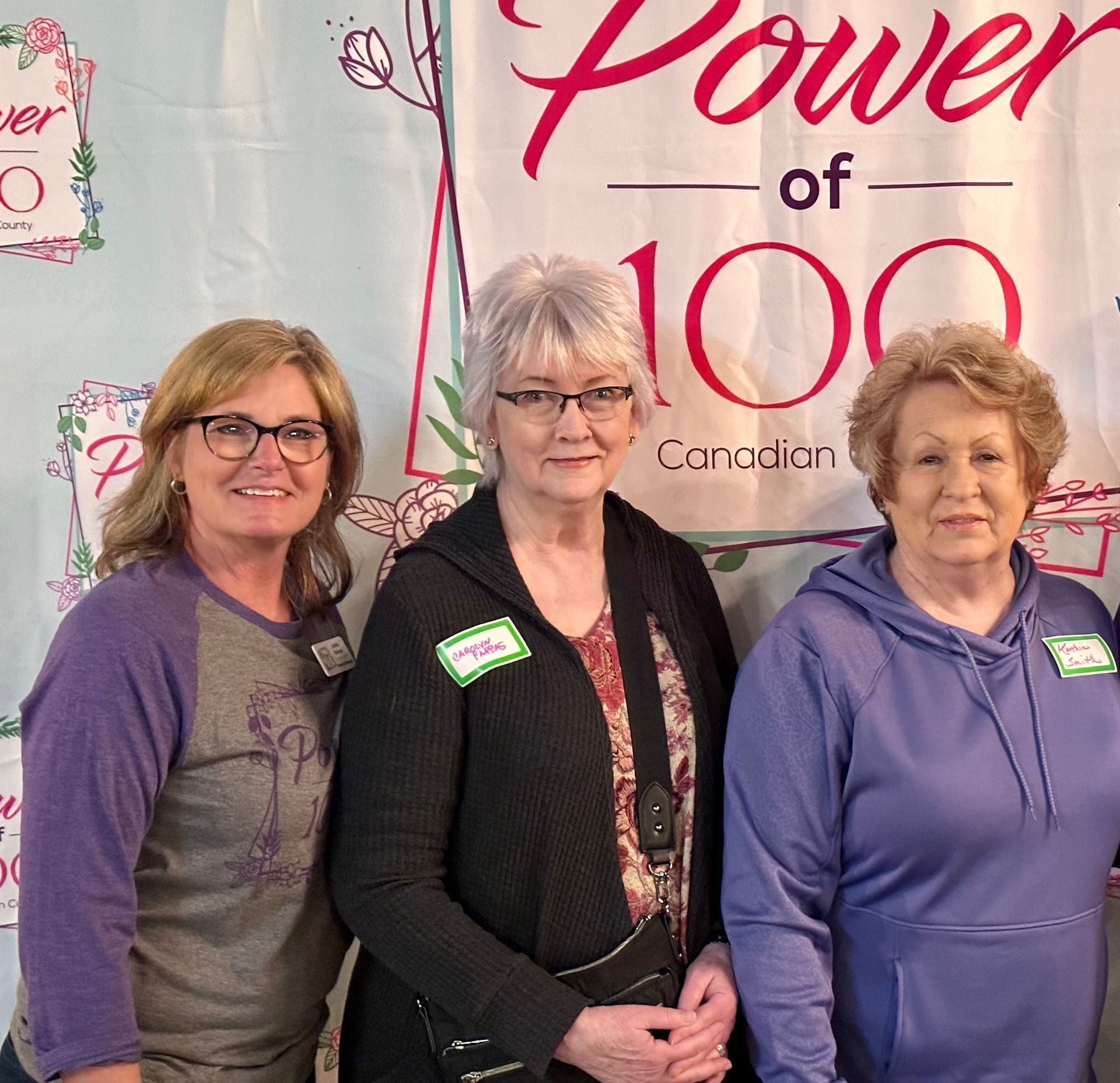 Three women standing in front of a sign that says power of 100