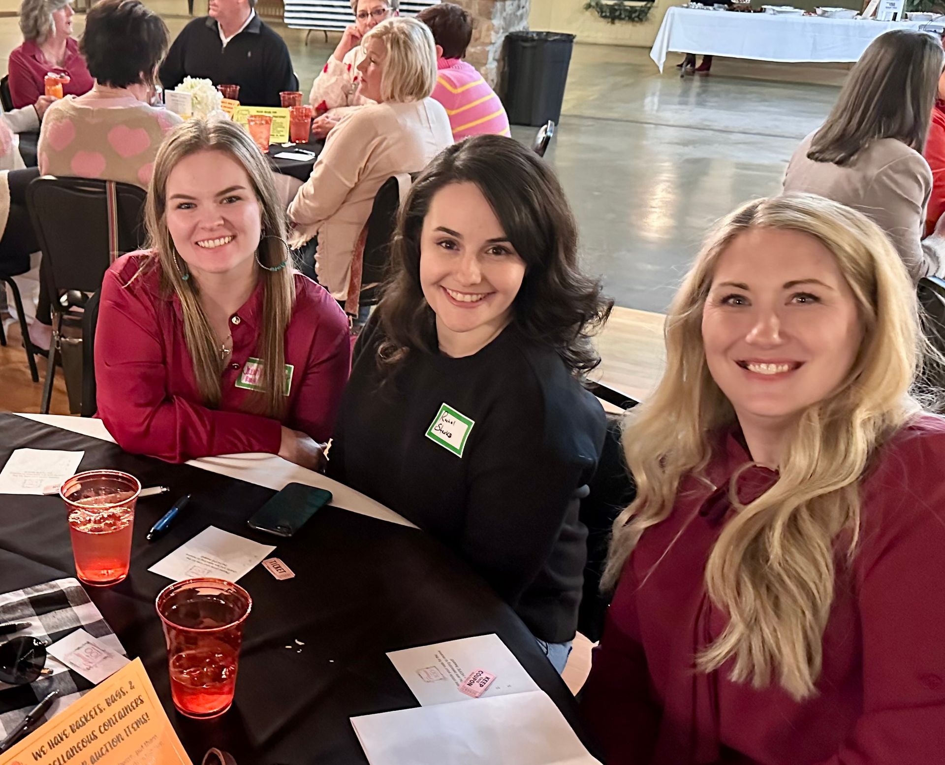 Three women are sitting at a table with drinks.